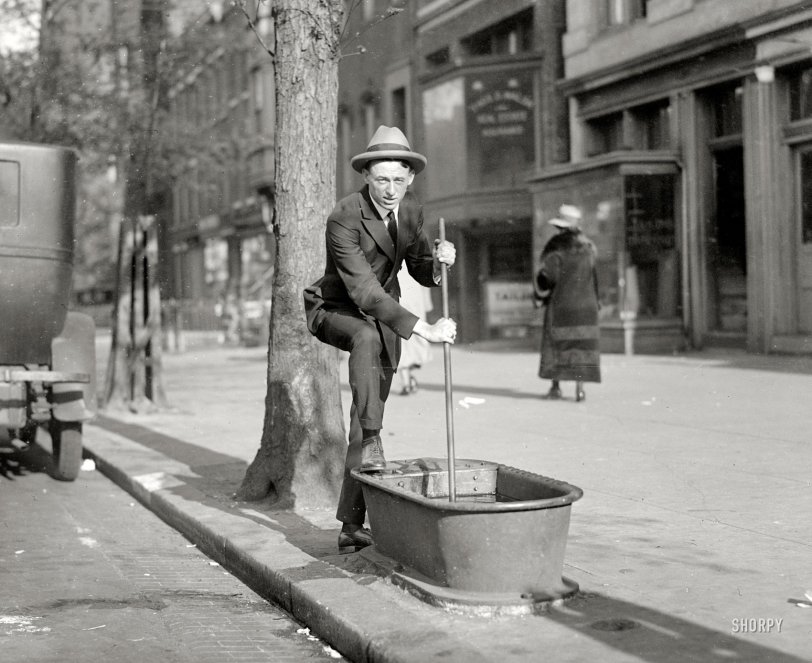 Photo of: Filling Station: 1924 -- Washington Post staff photographer Hugh Miller in 1924, clowning with an item that, along with lampposts and mailboxes, used to be common piece of urban street furniture: the sidewalk horse-waterer. National Photo Co. View full size.