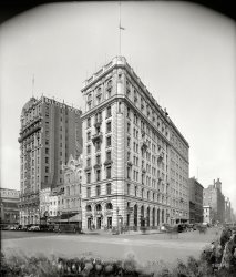 Washington, D.C., 1924. "Evening Star building." Offices of the Washington Evening Star newspaper next to the Raleigh Hotel on Pennsylvania Avenue between 11th (on the right) and 12th streets. Where there seems to be something of a mold problem. Harris &amp; Ewing Collection glass negative. View full size.
Hotel HarringtonThe Evening Star may have moved on, but the Hotel Harrington is still going strong. It would have been 10 years young at the time of this photo.
Flag at half mastCould it be for Woodrow Wilson who died that year?
Street viewGoogle street view.
View Larger Map
Technical questionI've noticed with a lot of these building photos that, despite being relatively wide angle, they don't suffer from the usual "converging vertical" problem that affects these shots. It's been a long time since I did any photographic theory - am I right in thinking this would have been done with a bellows camera that had the facility to shift the lens off-axis from the centre of the negative plate? So the lens and the plate both remain vertical, rather than panning the whole camera up to get the shot?
[Yes. - tterrace]
No Leaves on the TreesWilson died February 3, 1924, so it's likely this was taken within 30 days of that date.
A venerable Washington institutionThe Evening Star was at this location from 1881 until it moved to new quarters in Southeast in the alte 1950s. More about the building and the company can be found here.
Avoiding Converging PerspectiveThose lenses with the bellows in the middle worked like a charm. My medium-format Mamiya gear bag had one but it took me a while to get one for my Nikon F2.
I'm trying to remember whether it was a lens or an adapter to a lens.
Whatever it was, it worked great!
--Jim
Dueling PhotographersA rare Shorpy occurrence of the same building photographed by both Harris &amp; Ewing and the National Photo Company, which captured the same corner three years prior at Evening Star: 1921. Quite different perspective but very little has changed other than the billboard to the left and the removal of the Hart, Schaffner &amp; Marx Clothes signage at 1109-1111 Pennsylvania Avenue. Same mailboxes at the corner. To the right, up Eleventh Street Northwest is Hotel Harrington and the furniture showroom and warehouse of W.B. Moses and Sons.
Both are winter photos which may explain the removed awnings of the street-level stores.  Rather than shading a strolling summer customer, the panels are removed to let winter light into the store. 
Too Much Perspective Correction???While I fully agree with BigAl42's comment and also with tterrace's agreement I do have a thought about the subject matter shown here...
It may be just an optical illusion caused by the fancy masonry work near the top but it appears that the perspective correction on this image and some others previously shown on Shorpy have been over adjusted. 
In this image the building looks to be slightly wider at the top than it is at the bottom. 
(The Gallery, D.C., Harris + Ewing)