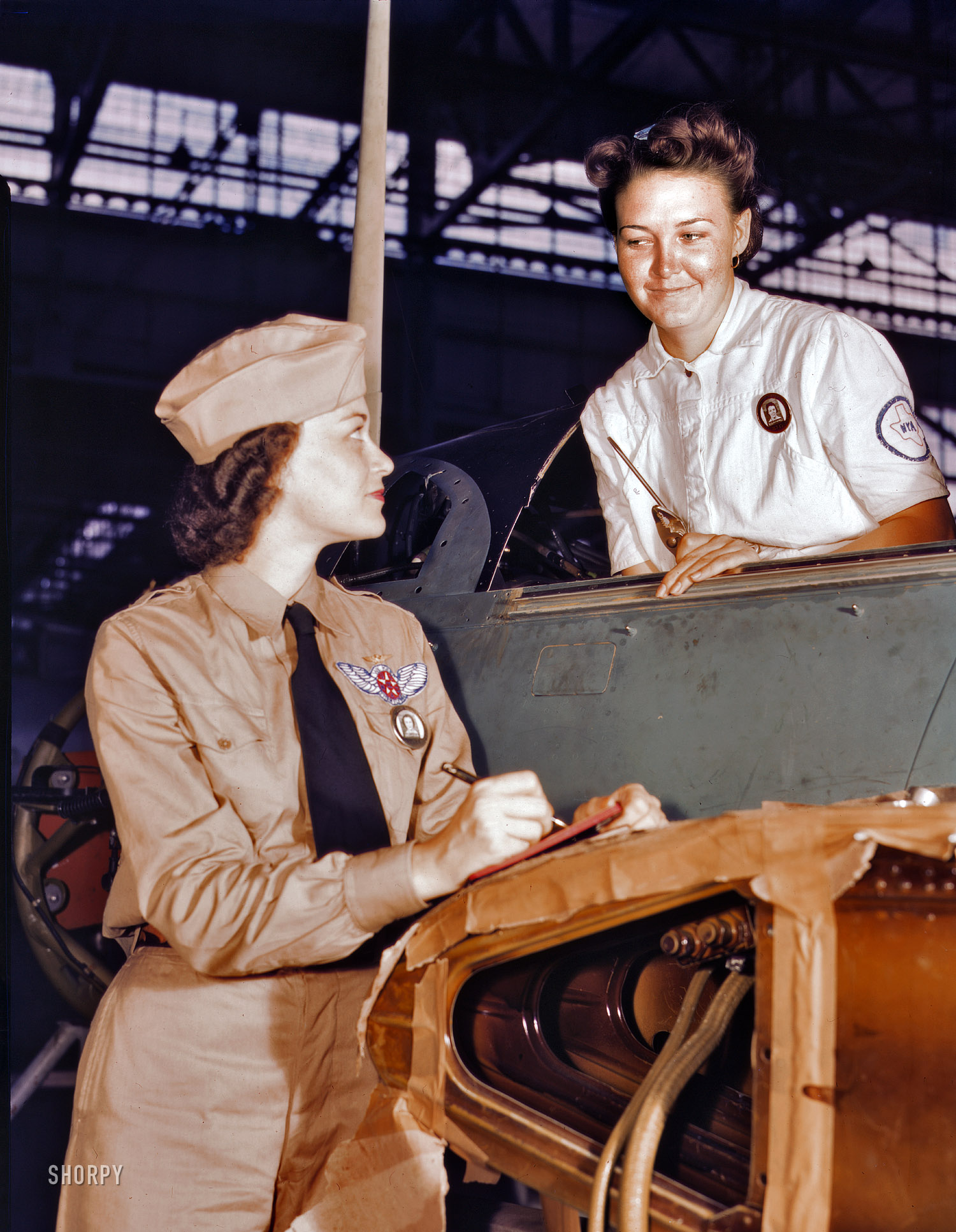 August 1942. "Formerly a sociology major at the University of Southern California, Mrs. Eloise J. Ellis (left) now "keeps 'em flyin'" at the Naval Air Base, Corpus Christi, Texas. She is a supervisor under civil service in the Assembly and Repair Department. It is her job to maintain morale among the women by helping them solve housing and other personal problems. With her is Jo Ann Whittington, an NYA trainee at the plant."  Large format Kodachrome transparency by Howard Hollem for the Office of War Information. View full size.