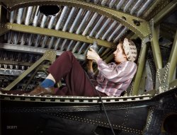 October 1942. "Douglas Aircraft plant at Long Beach, California. An A-20 bomber being riveted by a woman worker." (With, yes, a power drill.) 4x5 Kodachrome transparency by Alfred Palmer, Office of War Information. View full size.
Staying feminineLove the lipstick. 
RivetingShe must be just posing since where she is about to drill has already been riveted. Love the color! 
Compressed AirRosie is using a pneumatic (air-powered) drill, for those of you who care about such things.  Pneumatic hand tools are preferred in dusty settings where a motor spark can cause explosions.  Kudos to all the Rosies, including my grandmother.
A-20 &quot;Havoc&quot;Built by Douglas also converted to a night fighter P-70, sold to eight other countries, the Brits called it the Boston, even the Russians used them, they were called The Box, 7,478 were built, the cost of each aircraft was $74,000.
What&#039;s the problem, anyway?Before you can buck a rivet you do have to drill a hole. 
However, I rather hope that lady didn't inadvertently press the button on that drill, or at least its hose wasn't hooked up. Because another hole in this otherwise rather complete looking section would seem to be a bit superfluous. 
I can imagine the shop foreman grinding his teeth about those stupid press freaks who wanted to have a flashy but technically incorrect picture, and endangering the quality of his nice new aircraft section in the process.
By the way, if I had to guess I would place the lady in or near the center wingbox. 
Poor RosieWow!  Drilling in these close quarters without eye protection.  Not a good idea.
These gals did a tremendous job mobilizing America when it needed it the most.  I doubt if we could do that any more.
One of the lesser known planes.A friend's father flew one over the Pacific during the war. I was given his flying boots that show the wear and tear from the long hours spent flying missions. They are in excellent condition considering their age. I hold them in highest regard.
Keep &#039;em flying!I will always be in awe of the Greatest Generation.  While the boys were away fighting Hitler, Mussolini and Tojo, women like the one pictured here kept them armed and ready to take the battle to the enemy.  God bless 'em all.
Black &amp; DeckerShe is using a Black &amp; Decker 1/4" electric drill. You can see the electric cord hanging down. Those holes were not drilled in that position. They were drilled in the shop on a jig. Yes, it was a Photo-Op.
For the War EffortMy Mother worked as a Rosie at Willow Run, (now a defunct GM plant) and it was through that job that she met the man who became my Father. Ironically, he worked at Willow Run after the war. 
I think that&#039;s an electric drillThe housing is too fat for a pneumatic. An electric drill contains a big motor and gearbox. A pneumatic contains a turbine, and that's it. Note the slots just aft of the chuck, for cooling the motor. Also see the rubber cone strain relief on the cord, where an air tool would have a quick-release fitting. I'll admit the oversize cord does resemble an air hose.
She is wearing what I think of as "old lady pants", mainly because old people often continue to wear what they liked when they were young, without regard for current fashion. My memory for such things only goes back to about 1974, and both of my grandmothers wore pants like this. They were born eleven years apart, but both would have been the right age to work in this factory. 
Built &#039;em and flew &#039;emIn 1955, 32-year old civilian pilot Diana Bixby died in a borrowed A-20 when it ran out of fuel and she crashed in the Pacific off Baja, Mexico. She was well-known back then, having attempted a round-the-world flight in a De Havilland Mosquito with her husband but ending in India with engine trouble. Btw of the 7000+ A-20s built only 15 airframes or so survive, and I don't think there are any flyable. The A-20 was a single-pilot airplane and with a 385-mph top speed was relatively fast for the early 1940s.
Great Aunt Pinky&#039;s PlantMy great-aunt Pinky (she had red hair, thus the nickname) worked in that plant. She drafted rivet layouts for the workers to follow when building the planes. After the rivets were placed, she checked that they were placed correctly and were secure.
During the war, the entire plant was covered with camouflage netting. When photos of it were posted on barnstormers.com last year, I asked my cousin, her daughter, if Pinky had ever told her about the netting. Indeed, my cousin already knew all about it, but none of the younger generation in our family had ever seen a picture of it until last year.
During this same period, Pinky was going to Long Beach Community College at night to take classes to further her career as an engineer. She was an early trailblazer on that path for her gender, and worked for many years at Westinghouse among a department that was otherwise entirely male.
Rosie the RefinerWonderful picture. My Grandmother worked at the Shell refinery in Houston during this period making the AV gas for these planes. She was a Rosie the Refiner. She met my Grandfather there at the refinery (he was hit by friendly fire so was already home from the war).
(The Gallery, Kodachromes, Alfred Palmer, Aviation, WW2)