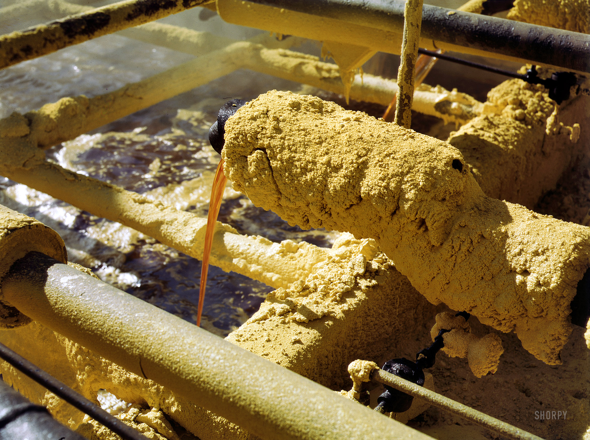 May 1943. "Melted sulfur from the wells pouring into relay station. Freeport Sulphur Co., Hoskins Mound, Texas." 4x5 Kodachrome transparency by John Vachon for the Office of War Information. View full size.