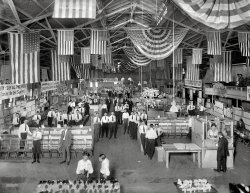 "Hahn's Coliseum, interior." A flag-bedecked footwear sale held by the Hahn's chain of shoe stores at Washington D.C.'s Center Market in July 1920. National Photo Company Collection glass negative. View full size.
11 o&#039;Clock BulletinOver 200 salespeople! Click to enlarge.

Reserve Stocks at Consistent ConcessionsAm I right in interpreting that all these men looking at the camera are sales clerks waiting for customers?  They are all wearing similar clothes: rolled-up sleeves and no jackets.  Would any business ever ask patrons to pose in this way for the camera? I count 60+ clerks, an astounding ratio of salespeople-to-square-footage compared to today's norms.



Washington Post, June 20, 1920.

The Pick of the Market in Women's White Shoes
Joins the Great Mark-Down


The fame of Hahn's wonderful Mark-Down has spread through the market&mdash;and makers are giving their co-operation in offering us their reserve stocks at consistent concessions. We are very discriminating in what we accept, however, for even at Mark-Down prices the Hahn standard of quality must be maintained. &hellip;

The Mark-Down is making broken lots and short lines rapidly and as fast as they are created we're turning them into the &#8216;Bargain Sections&#8217;&mdash; where you can make your own selection&mdash;and our assistants will help to fit your choice.

Tomorrow you'll find rare choosing&mdash;especially of the popular White Shoes&mdash;the variety is large; and so are the values&mdash;and you can be sure of your size in one style or another.
Shoe salesmenstanton_square's speculation about all those guys being sales clerks is correct. Until recent times (well, if you can include my childhood years as "recent") each customer was waited upon individually, even in the humblest shoe store. The stock was kept in a mysterious (to me) area accessible only to the salesman via a drapery-shrouded portal. I still feel a bit weird doing everything myself in these self-service days. Presumably this photo was taken before the doors were opened to hordes of shoe shoppers yearning to be shod.
Center MarketSo here you see why the building would be familiar in the Herald ad. (BTW I bought most of my shoes from Hahn until they went out business in 1995.)
&quot;I&#039;m born and bred to be a shoeman&quot;I think I see Al Bundy!
Odd man outThat's his bow tie and he's stickin' with it!
Not WalmartIt's amazing to see so many people and not one who is obese.
Crisis of solesThat ad is the first I've heard of the Great Shoe Glut of 1920. Was that a thing, or mere ballyhoo?
MemoriesWe used to shop at the Hahn Store at Albemarle Street and Connecticut Avenue NW, now all I have as a reminder is a steel shoe horn they used to include with a new purchase.  An excellent store with a good staff.  But that shoe horn takes me back about 56 years to when I was in high school.
Late again!Did I miss the sale??  Where are the crowds of consumers rushing to stock up on shoes I'd heard about? 
(The Gallery, D.C., Natl Photo, Stores & Markets)
