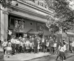 Washington, D.C., 1920. "Dixie Theater crowd, H Street." Now playing: "Hidden Dangers" (Episode 2, "The Murder Mood"), "The Primal Lure" and "When Cowboy Was King." Kids get in for 11 cents! Next door: People's Drug Store No. 5. National Photo Company Collection glass negative. View full size.
Fast ForwardAbout 1946 after school one afternoon, I went to the Loews 167th Street Theatre in the Bronx. Previously I had brought two milk bottles into a local grocer and collected the 3¢ deposit on each, I added 3¢ of my own and bought a 9¢ ticket to a double feature. 
Eleven centsI remember the Saturday matinee for 7 cents in 1951 for two cowboy movies, a newsreel, the Three Stooges and a cartoon or two. 
A rough looking bunchI can't recall a more delinquent looking bunch on Shorpy, even the Newsies look downright respectable compared to these kids.
It took two Cops and a Billy Club to keep them in line!
Dime StoryThere was a beat-up, run-down old movie theater on a side street in Poughkeepsie that showed third-rate stuff for about a dime. The joke among us kids was that you had to take two pieces of bread with you if you went in there : one to sit on and the other to feed the rats with.
A curious mixture of scruffy and neatI'm surprised that bow ties appear to be part of police uniform. Also, one would have hoped that they would have had their coats done up for the photo!
I'm presuming that these are in fact cops.
Looks like Larry Semonin the poster behind the bald guy.
Larry Semon and other thingsThe lobby cards to the left of the box office appear to be for "Humbugs and Husbands", a Larry Semon Vitagraph comedy from 1918. 
The Primal Lure, which was directed by William S. Hart himself, was originally released in 1916.
When Cowboy Was King was copyrighted Sept. 20, 1919 and directed by Aubrey M. Kennedy. 
Hidden Dangers was a 15 part 1920 serial directed by William Bertram that critic George Ralph Doyle called "(the) worst serial I have ever seen". Serial Squadron says it's "entirely lost" (they've published a book based on the original press materials), and that's a shame because it sounds kind of nuts, really. It involves a doctor whose  Jekyll-and-Hyde complex turns him into a super villain that commits crimes with "the mysterious and powerful 'double X ray'". I'd pay a dime to see that. How about you?
(The Gallery, Bicycles, D.C., Kids, Movies, Natl Photo)