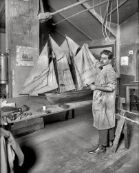 January 22, 1921. Washington, D.C. "Paul E. Garber (Smithsonian museum)." National Photo Company Collection glass negative. View full size.
It&#039;s a dirty jobbut someone had to do it.
His Pants Say FloodShouldn't he be working on an ark?
Restoring the Boat?If that's his reference picture on the left he's never going to get it to look like that!
Sky&#039;s the LimitMr. Garber joined the Smithsonian the previous year (1920), and would eventually become the first head of the Institution's National Air Museum. Now, the Paul E. Garber Preservation, Restoration, and Storage Facility is spread among 32 buildings in Maryland. 
And in his spare time, Garber led the crusade to legalize kite-flying on the National Mall. 
So Much More Than a Model Fixer-UpperGarber can be said to have been the heart and soul of the Smithsonian's National Air and Space Museum (NASM). He joined the Smithsonian the year before this photo was taken after working for the U.S. air mail service. He died in 1992 at age 93. Historic aviation treasures he personally was responsible for obtaining for the Smithsonian are many including Charles Lindbergh's Ryan that flew the Atlantic in 1927, the Wright Brothers' plane that flew at Kitty Hawk in 1903, and the B-29 that dropped the first atomic bomb on Japan, the "Enola Gay" (named after pilot Paul Tibbet's mother). Here's my photo of the Enola Gay.  
Following instructionsI hope the drawing on the wall wasn't the plan for what was to be built.
&quot;Clipper&quot; Fishing Schooner?The model also went on to bigger and better things, like Mr Garber.  I believe it is one of the "clipper" fishing schooners (c. 1855-1870) described by Howard I. Chapelle in two books, "The History of American Sailing Ships" (1946?) and "American Fishing Schooners" (1973).  I think the model, prettied up with clean, non-stained sails and re-painted, is currently in a large display case with a number of other sailing small craft, in the National Museum of American History.
The "clipper" schooners were technically very advanced and achieved unusual speeds, but they had "the fatal ability to capsize when heeled beyond a certain point" (Chapelle's own words) and triggered a series of bad accidents.   Eventually, owners switched to the seaworthy deep-keel schooners that fished the Grand Banks from about 1895 to 1933.  South Street Seaport's "Howard" is one of the earliest of these.
Locomotion (not Little Eva!)It's behind you. George Stephenson's 'Locomotion' introduced on the Stockton &amp; Darlington Railway in 1825. There's a working replica a the Beamish Museum in County Durham.
RR observationsThe rail buffs have weighed in.  The photo in back of the modelmaker is Pennsylvania RR's JOHN BULL.
Locomotive(s)The locomotive pictured on the column is clearly the Stourbidge Lion. The vital clue is the inscription below the photo which says 'The Locomotive "Lion"'. 
However, I don't think that's the image that z396z28 is talking about. Directly behind Mr. Garber, visible between his right arm and his head is another photograph of a railcar and locomotive. I think THAT is what is being identified - rightly or wrongly - as JOHN BULL.
No BullThis (Locomotive on picture on column)is actually the Stourbridge Lion,  British built for use in the USA.   Smaller than the "John Bull" and larger than "Locomotion".    Look close at the caption and compare with the Lion's pictures.    
(The Gallery, Boats & Bridges, Natl Photo)