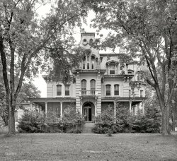 &nbsp; &nbsp; &nbsp; UPDATE: The location is the old Maplewood estate near Lewinsville in Fairfax County, Virginia; the 1874 Second Empire mansion, at 7676 Old Springhouse Road in what's now McLean, was known as Villa Nuova. The residence was demolished in 1970; whatever connection it might have had to Woodrow Wilson is unknown. Hat tip to Shorpy member Wiggy.
Circa 1925. "Woodrow Wilson house." No other information provided. (Not pictured: Tweety and Sylvester in the parlor, going at it hammer and tongs.) National Photo Company Collection glass negative. View full size.
No Way!When I showed my wife this photo, and casually commented how nice it would be to live in such a big house, she had one comment:
"You better hire a cleaning service, 'cause there's NO WAY I'm gonna be cleaning all those windows!"
Masnard roofThe finest quality Second Empire buildings were usually masonry up to the bottom of the top floor, then wood frame on up.  The lightweight wood "Masnard" framing allowed for such free-form, Munster-like extravagances as we associate with the style.  Unfortunately, such buildings are notoriously leaky and suffer badly from even short periods of neglect.
[Ahem. The word is MANSARD, not "masnard." -Dave]
Norman and MotherThis house looks perfect for the Bates family.
WOW, beautiful Second Empire house!Any ideas as to where this is/was located in DC?  Inquiring minds want to know.
Wilson connectionInformation on Woodrow Wilson's residences is easily available online.  What's not so easy is figuring out when, or if, he lived in this house: it's not the Virginia house where he was born; it's neither of his boyhood houses, in Georgia and South Carolina; it's none of the three houses where he lived in New Jersey; and it's not the house he bought shortly before leaving the presidency and where he died a few years later.
Porch ColumnsWhat an interesting detail for the top of those columns.  An exquisite house, very handsome. Just need to know the location, nothing else needed.
The RingerWoodrow Wilson is always the name that trips up folks when you ask them to tell you the eight presidents born in Virginia. 
Most quickly think of Washington, Jefferson, Madison and Monroe, and may eventually come up with Harrison, Taylor and Tyler. But no one expects a 20th Century president to have been born in Staunton, Va.
Maplewood aka Villa NuovaIn the 60s we used to pass this marvelous house on the way to my father's office and it always fascinated me. It was located on Chain Bridge Road (VA 123) between Vienna and McLean, Virginia, near Tyson's Corner (which I just remember as a real corner--the intersection of two, two-lane roads with a junky little country store).  
The marvelous mansard was demolished 1970, alas -- but at least HABS took photos. I don't know anything about a Woodrow Wilson connection.
[Thank you, Wiggy! - Dave]
PuzzledWhy have so many of these lovely houses that appear in Shorpy pictures been demolished?
[House old and decrepit, land value increases, owners sell out. - Dave]
 Why, thank you, Thing!Photo brings another family to mind:
They're creepy and they're kooky,
Mysterious and spooky,
They're all together ooky,
The Addams Family.
Their house is a museum
Where people come to see 'em
They really are a scream
The Addams Family.
Snap, snap!
MapleWood A 1956 newspaper article below refers to the house as, "the summer home of Woodrow Wilson."  I can't find any contemporaneous accounts to confirm that but then it is probably not the sort of thing reported in newspapers.  Owners included Brigadier General William McKee Dunn in the 1870s and Charles Brodt in the 1910s.  Sidney and Ethel Ulfelder bought the property in the late 1920s and held it for 5 decades. Control of the property was passed to their son-in-law Rudolph Seeley, who quickly razed the building soon after Mrs. Ulfelder's death before it could be declared a historic landmark. 



Washington Post, July 30, 1956.

McLean Seeks U. of Va. Branch


A McLean, Va., group came forward with a last-minute  proposal yesterday for the location of the Northern Virginia branch of the University of Virginia at the historic Maplewood estate of Dr. and Mrs. Sidney Ulfelder. They also suggested that the proposed Fairfax County Hospital be located on the property.

The 500-acre estate, which includes a 24-room mansion which at one time was the summer home of Woodrow Wilson, will sell for $2500 an acre, they said. &hellip;

The McLean Group, made up of French Trammell, Robert A. Alden and O.L. Brandenburger, met yesterday with Col. Rudolph G. Seeley, manager of the estate and son-in-law of the Ulfelders. &hellip;




Washington Post, November 12, 1969.

Ethel Ulfelder, 84, a major land owner in Fairfax County and the widow of Dr. Sidney Ulfelder, a physician at the American-British Cowdray Hospital in Mexico City from 1900 until his death in 1959, died Monday after a brief illness in Mexico City.

She owned the 512-acre Maplewood Farm, part of which is now the Tysons Corner shopping center, the Westgate Industrial Park and nearby sections of what is now the Beltway and Dulles Airport access roads. The old Maplewood house itself is now the Westgate office, on Rte. 123 in McLean. &hellip;



Washington Post, February 25, 1970.

Wrecking Crew Steals March on History Buffs in Fairfax


Wrecking crews stole a march on history buffs last weekend. A 100-year-old Victorian mansion the buffs had hoped to preserve was demolished and apparently none of them know anything about it until it was too late. 

The 24-room, yellow-painted brick home, known as Maplewood, was torn down at the Westgate Research Park near Tyson's Corner to make way for construction of another industrial building. &hellip;

&#8220;We are just terribly depressed, surprised and shocked,&#8221; said Joyce Wilkinson, chairman of the Fairfax County Historical Commission.  She and other commission members claimed that Rudolph Seeley, executive vice president of Westgate Corp., told them last October that the structure would not be torn down for up to three years and not sooner than one year.  

Seeley said the demolition was ordered because the &#8220;house is standing on very valuable, highly taxed land&#8221; and was &#8220;not a particularly architectural gem under any stretch of the imagination.&#8221;



Washington Post, January 6, 1988.

Col. Rudolph G. Seeley, 72, a Fairfax County civic leader and developer who helped pioneer the explosive commercial growth of the Tysons Corner area, died of cancer Jan. 4 at his home in McLean. &hellip; 

It was not until after the war that Col. Seeley moved to the Washington area. The family of his wife, the former Martha Ulfelder, had been farmers in the Tysons Corner area since the 1920s, and the colonel became manager of their dairy business during the late 1950s. Construction occurred between 1958 and 1964. There were 14 interchanges on the highway in Fairfax County alone. The idea that major commercial development would take place so far from downtown Washington was thought to be preposterous. Where the Beltway passed near Tysons Corner there was a feed store, a gas station, a restaurant and a general store. Much of the Ulfelder farm was taken for the Beltway right of way. Mindful of development opportunities, Col. Seeley led a group in acquiring more acreage with a view to rezoning it for commercial use. 

The wisdom of this move was affirmed with construction of the Dulles Airport Access Road. The Seeley-Ulfelder holdings were at the intersection of Rtes. 7 and 123, roads that had existed since Colonial times. With the building of the Beltway and the Dulles Access Road the land was better served by major highways than any location in Northern Virginia. In 1961 Col. Seeley and Gerald Halpin, a former officer of Atlantic Research Corp., combined land holdings to build a research and industrial park and they helped found the Westgate Corp. to carry out their plans. Col. Seeley also was part of a partnership that leased land to Maryland builders who erected the Tysons Corner Center. It opened in 1968 with three anchor stores and about 70 smaller businesses.  &hellip;

Bravo!Best Shorpy caption ever!
(The Gallery, D.C., Natl Photo)