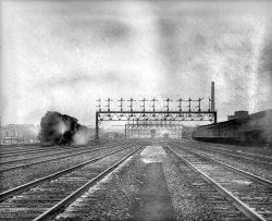 Washington, D.C., circa 1921. "Union Station tracks." Receding in a haze of soot, steam and mildew. National Photo Company glass negative. View full size.
The Pennsy E6looks very archaic for an engine running in 1921. It still has a box headlight and tailrods - which means its not yet superheated, so its an E6, not an E6s
Unit number5218 or 5318 - On whose roster?  Anyone?
The locomotiveIt's a Pennsylvania Railroad class E6s 4-4-2 Atlantic.
Their Majesty I have always been exposed to trains. Born in Brooklyn, under the EL, raised in Queens, home of the LIRR, and now living a mile from the GE Alco plant, where more coal and diesel locos were built than anywhere else. Pictures cannot convey the awe experience savored at the side of one of the industrial age's most perfect mobile power houses'. 
(The Gallery, D.C., Natl Photo, Railroads)