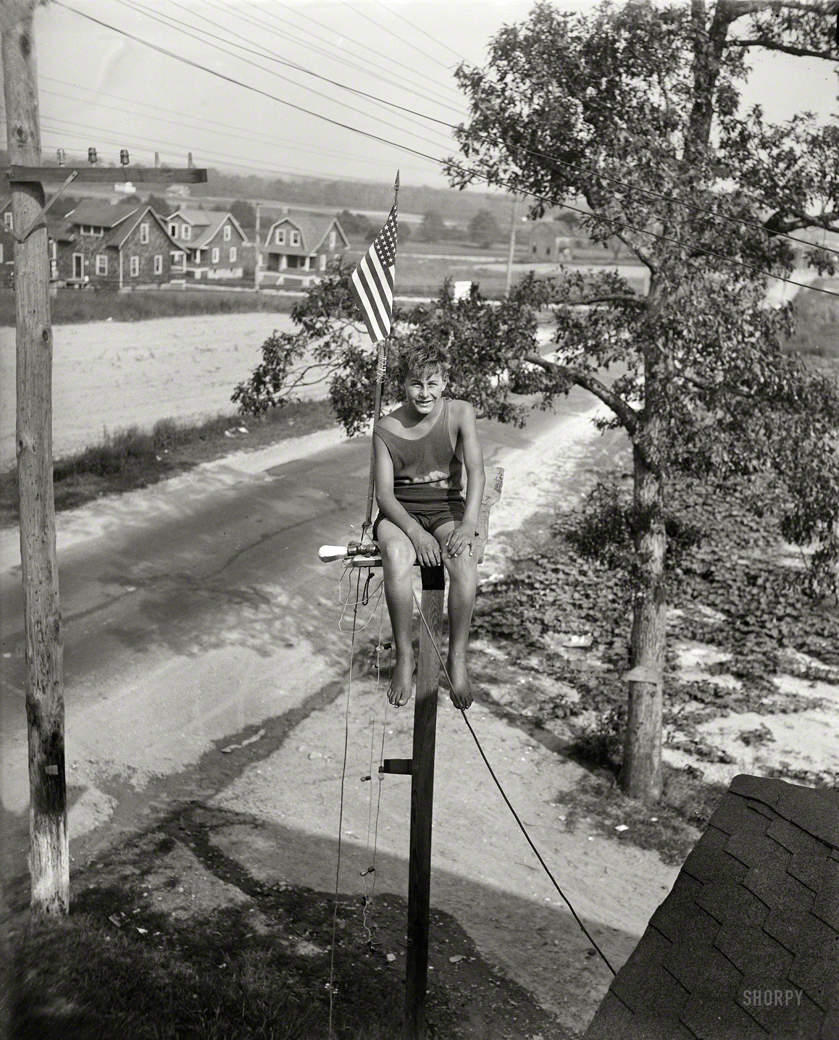 UPDATE: The Library of Congress has given this photo a caption.

September 3, 1929. "Maryland youth breaks pole sitting record. William Ruppert, 14-year-old youth of Colgate, Maryland, as he appeared atop the flagpole in the yard of his home yesterday after breaking the pole sitting record of 23 days set by Shipwreck Kelly. Young Ruppert, who started his sitting on August 1, has worn out three pairs of trousers so far. He says he expects to stay up 30 days more. The pole is 18 feet high." Note the light bulb rigged to the seat. View full size.
