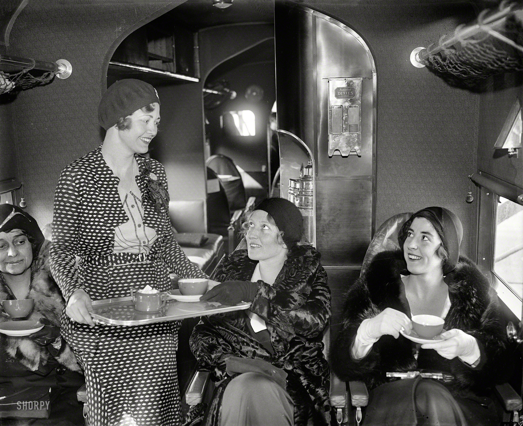 UPDATE: The photo now has a caption.

January 10, 1930. Tea time in the air. Miss Wanda Wood, hostess for the Eastern Air Transport, serves tea for two -- Misses Charlotte Childress and Elizabeth Hume, aboard one of the line's passenger planes. The company provides bridge, tea and cigarettes, with hostesses to arrange the bridge games and serve the tea.

We seem to be aboard an aircraft in this unlabeled glass negative from the Harris & Ewing collection. Beverage service uses real china as well as "Individual Dixies." Who can identify these ladies' means of conveyance? View full size.