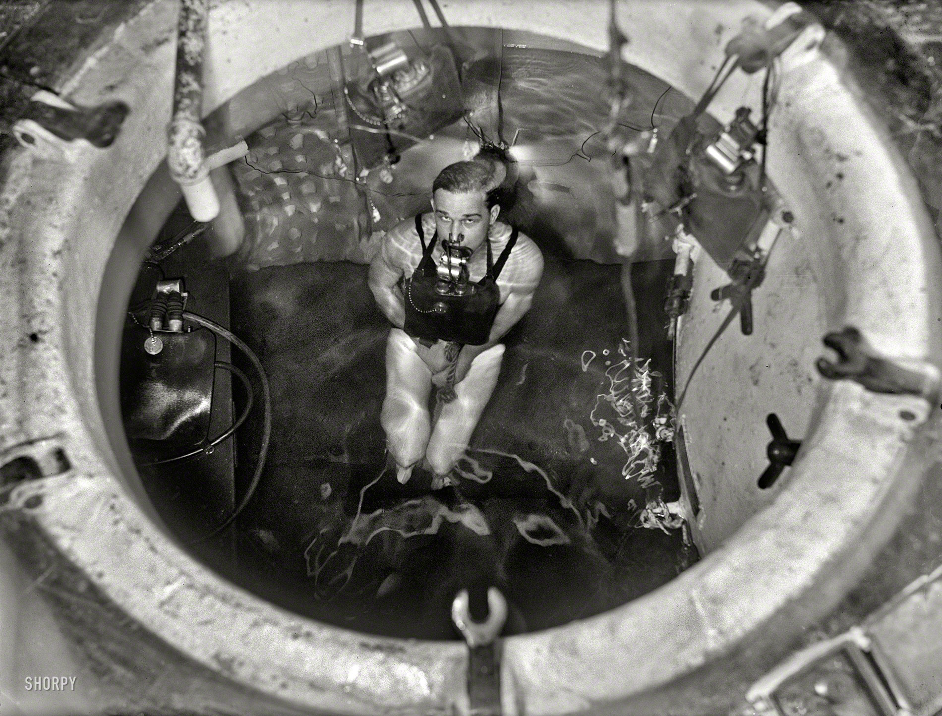 Washington, D.C., 1931. "Man partially submerged in tank with breathing appar&shy;atus." Last seen here on this guy, probably at the Navy Yard. View full size.