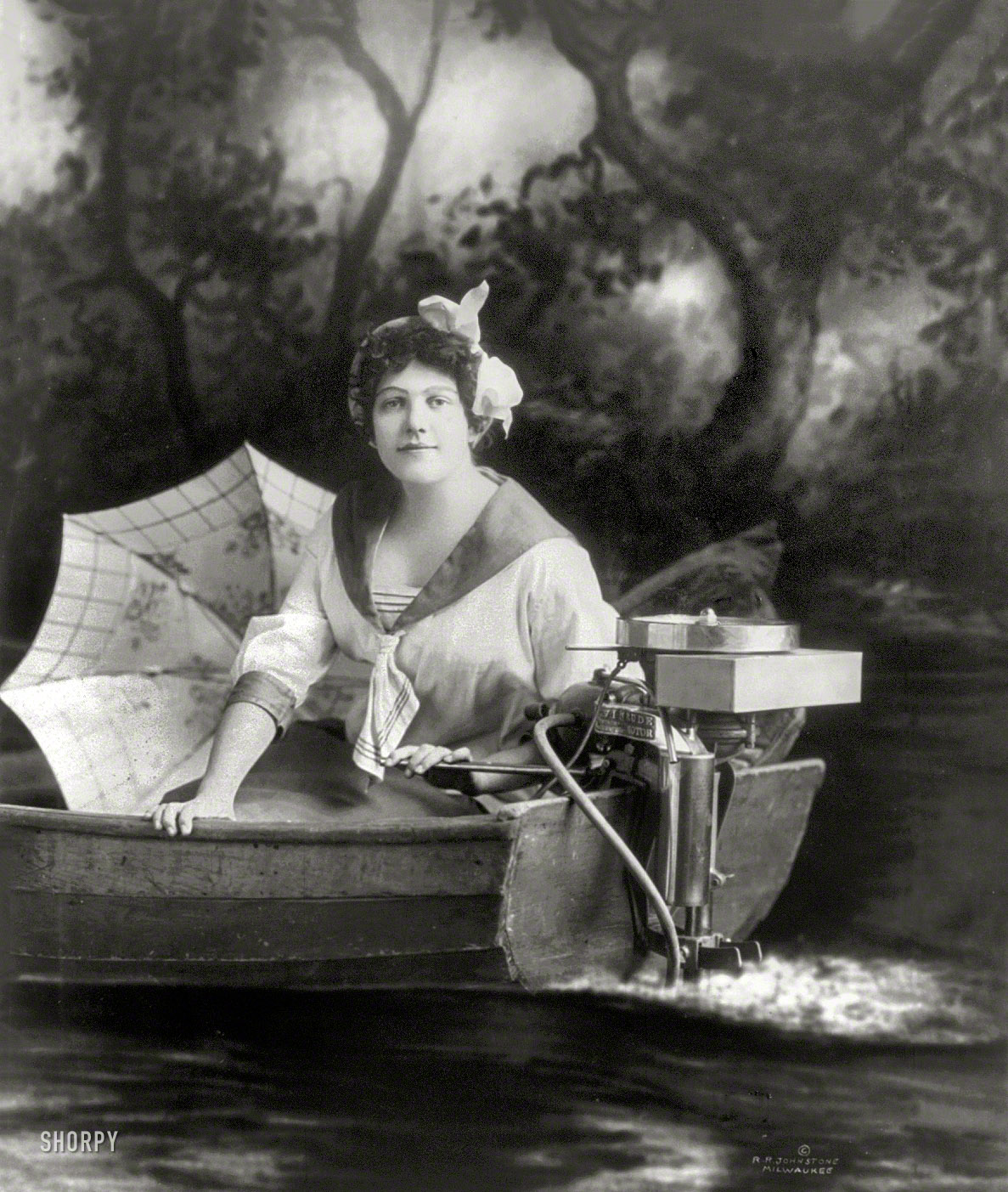 1913. "Young woman posed with an Evinrude outboard motor." Able to outrun any lad with a Johnson. R.R. Johnstone photo studio, Milwaukee. View full size.