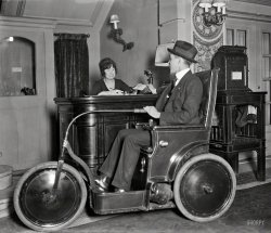 January 1922. Washington, D.C. "Man in three-wheeled vehicle." Which is, according to the nameplate, a ____G CAR. 4x5 glass negative. View full size.
BeautifulWall sconces and wall embellishments, so typical in the 20's!  All would be gone by the 40's, replaced by bland industrial looking light fixtures and plain blonde walls.
Custer Chair Car?The vehicle looks a lot like the  Custer Chair Car, featured on the very informative blog called Just A Car Guy, which concerns all things transportation-related.
[It could be -- both are made by a "Specialty Co." -- although our chair-car has a G in the name. - Dave]
The Segway of its eraJust need to find enough room to do U-turns. Fairly easy in hotel lobbies, but hallways? Concept good, execution needs work.
[Next stop, Walmart. - Dave]
Last standIt certainly does appear to be a Custer Car. A close-up of the rear hub on a similar photo appears to show the embossed legend "CUSTER CAR".
The inventor, Levitt Luzern Custer, filed a 1919 design patent for a very similar-looking "juvenile automobile." (It's obviously not the same design, but the resemblance is clear.)
[Two "juvenile" Custer Cars can be seen here and here on Shorpy. - Dave]
The Wheels!About 60 years ago I had an old red wagon from the early 1930s that came off a hill and got hit by a car on Long Island. I bounced six times and was OK but the wagon was a fatality. The wheels were smaller than those in this photograph but I remember the style and inside the black rubber was all "fire engine red".    
StairdownI'm sure that vehicle was quite practical given the abundance of wheelchair ramps in 1922.
Tare weightI bet that thing weighs a ton (short, long or figurative.)
Restored Custer CarVideo linked from this blog.

Demon of the RoadsThe driver is none other than L. Luzern Custer himself, piloting what the caption describes as a "Cootie Car." (Washington Post, Jan. 21, 1922)

Although another clipping (The Daily Ardmoreite, 17 Nov. 1920) describes a different vehicle, a toy electric car for children similar to the ones here and here, as a Cootie Car:

(Technology, The Gallery, Cars, Trucks, Buses, D.C., Harris + Ewing)