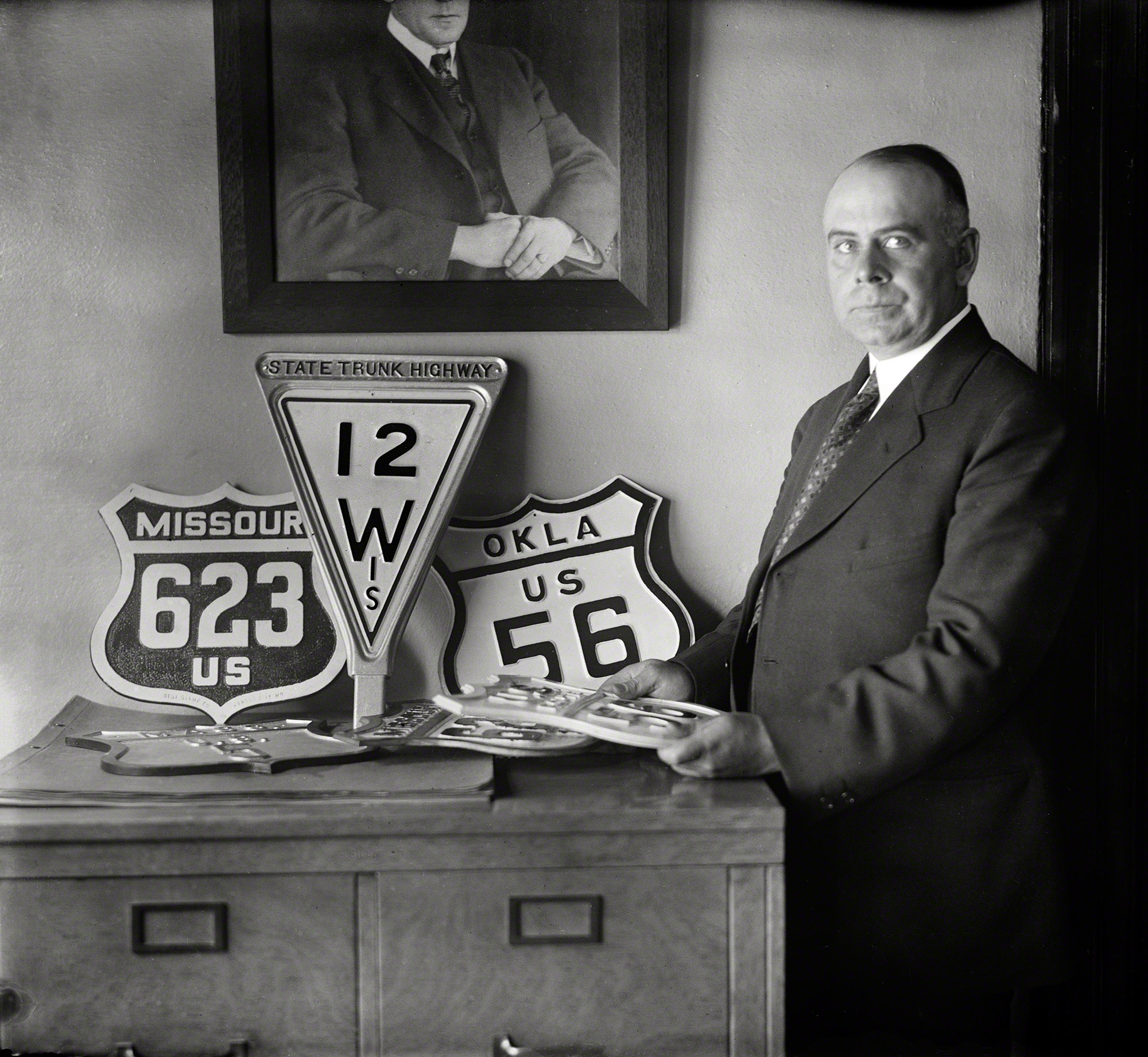 &nbsp; &nbsp; &nbsp; &nbsp; The conferees representing the highway commissions of several States, who met in this city during the present week under the auspices of the Joint Board of State and Federal Highways, reached a wise decision when they agreed to create a group of interstate roads to be known as United States highways &nbsp; . . .
 -- Washington Post editorial, April 25, 1925
Washington, D.C., 1925. "No caption (man with highway signs)." Early waypoints on the road to uniform route designations and the standardization of highway signs. Harris & Ewing Collection glass negative. View full size.