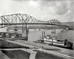 1898. Winona, Minnesota. "Bridges over the Mississippi. Sternwheeler Lafayette Lamb." 8x10 inch glass negative, Detroit Publishing Company. View full size.
Memories To MeI delivered many a railroad car from the Wisconsin side working as a brakeman for the BNSF in the 1970,s. The railroad swing bridge was destroyed by fire in the 1980's. The traffic bridge that replaced this one is in the process of being rebuilt with another one added. Great picture from a simpler time.
Minnesota VikingNice touch, the elk rack atop the Pilothouse.
The breakers!I like the pre-ice breakers for the railroad bridge pillars.  Never seen anything like that before.
Also, the railroad drawbridge looks structurally similar to the one still in use in Vancouver Washington on the BNSF, although this one is single main line.
Size MattersCaution: Rowboats are much larger than they appear. So large, that bridges swing out of the way for them.
Looks like the remains of the RR bridgeView Larger Map
One personsitting on what must be the world's largest park bench.
Lady in WhiteIt looks like there's a lady taking the air on the boiler deck aft. Maybe she's on her way to visit her cousin in Red Wing or Frontenac. The steamboat seems to be home-ported at LaCrosse, which the locals on that part of the river call God's Country.
Back when a bridge was a bridge.For thousands of years bridges have been a combination of art and engineering.  Many times, the character of a city was defined by its bridges.
It's only been in the last 50-60 years that bridges have become dull, boring affairs.
Lumber baron Lafayette Lamb (1846-1917)The namesake of the steamboat had inherited a saw mill company, C. Lamb &amp; Sons of Clinton, Iowa, from his father Chancy. In the immediate aftermath of the Civil War, young Lafayette oversaw a fleet of the company's steamboats that was used for towing logging rafts down the Mississippi River to the mill. By the time of this photo, that part of the company's business had declined along with the supply of white pine timber floating down the River. By the time of Lafayette's death in 1917, the company's primary interest was a large saw mill in Charleston, Mississippi.   
The viewBefore the next new bridge (now) courtesy the USPS.
My humble burg!Nice to see some love for our beautiful town. The section of the railroad bridge is indeed still there, and as mentioned, plans are underway for a new interstate bridge.
I'm continually fascinated with the amazing old photos of this town, and how much it's changed. Many beautiful old buildings are no longer here, replaced by parking lots or newer structures that lack the character and feel that the old ones have. Guess that's not too uncommon, but a shame nonetheless.
(The Gallery, Boats & Bridges, DPC)