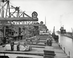 Lake Erie circa 1900. "Unloading ore at Conneaut, Ohio. Brown conveying hoists." 8x10 inch glass negative, Detroit Publishing Company. View full size.
Didn&#039;t change much for 80 years.During college (1981), I worked on an ore ship. The Str Paul H. Carnahan- National Steel Corp. It was one of the last ones on the lakes that didn't have a self-unloading boom. When we went from Duluth to Cleveland or Sandusky or, yes, Conneaut, we were unloaded with this same type of machinery.
It might have been updated with Diesel power or Electricity - I don't remember.
I worked in the Galley, so I didn't have to deal with opening the hatches as in the pic.
Ahhh... youth.
Brown Conveyor UnloadersWow!  Those things must have taken FOREVER to unload even a small boat (on the Great Lakes vessels in captive service on the lakes are called "boats", not ships) of, maybe, 5,000 tons.
I've never seen a picture of one of these before.
The only way I can visualize, at that time, to fill that bucket suspended from the trolley of the conveyor is to have workers hand shovel the ore in the hold into the bucket!  In those days, laborer really meant LABORer.
I've always thought the Hulett unloaders that unloaded boats for the next half a century were clumsy, but they were sure a vast improvement over these Brown monsters.
Todays conveyor equipped "self-unloader" boats are a quantum improvement over the Huletts.  
A transportation vehicle (railroad car, semi-trailer, boat/ship, stagecoach, or aircraft) only makes money for its owner when it's moving.  Anything that can reduce terminal time is money in the bank.
BrownhoistsThe Brownhoists were all gone by 1981. Ore would have been unloaded by Huletts, which were incredible machines. Here is a link to a You Tube video of them. 
Notice tied up alongside this ship is the ubiquitous "bum boat". literally a floating general store, found in almost every Great Lakes port back then. I think they are all gone except perhaps the one in Duluth.

Hand shoveling, Browns, and HulettsYes, the Huletts were a giant leap in unloading iron ore, stone, etc. over the Browns, but before the Browns, there was hand shoveling.  So, the Browns revolutionized cargo unloading, and then the Huletts did it again.
BTW, the Huletts in the video were in Cleveland.  Several were scrapped and several were dismantled.
18 men and 1 Brown Unloader could unload 100 tons per hourFor "tons" of information on the unloading of ore boats and more, see
the Google ebook
Iron Ore Transport on the Great Lakes: The Development of a Delivery System to Feed American Industry
 by W. Bruce Bowlus.  "This detailed history recounts innovations in shipping, the improvement of channels and harbors, the creation of locks, technical advances in loading and unloading equipment..."
A preview of the book is available at http://goo.gl/pukcj4 (try searching the book for [Brown]
Incredibly interestingI forwarded this to my daughter the engineering student and she was impressed.  Thanks to Clare for the link to the video of the Hullets.
(The Gallery, Boats & Bridges, DPC)