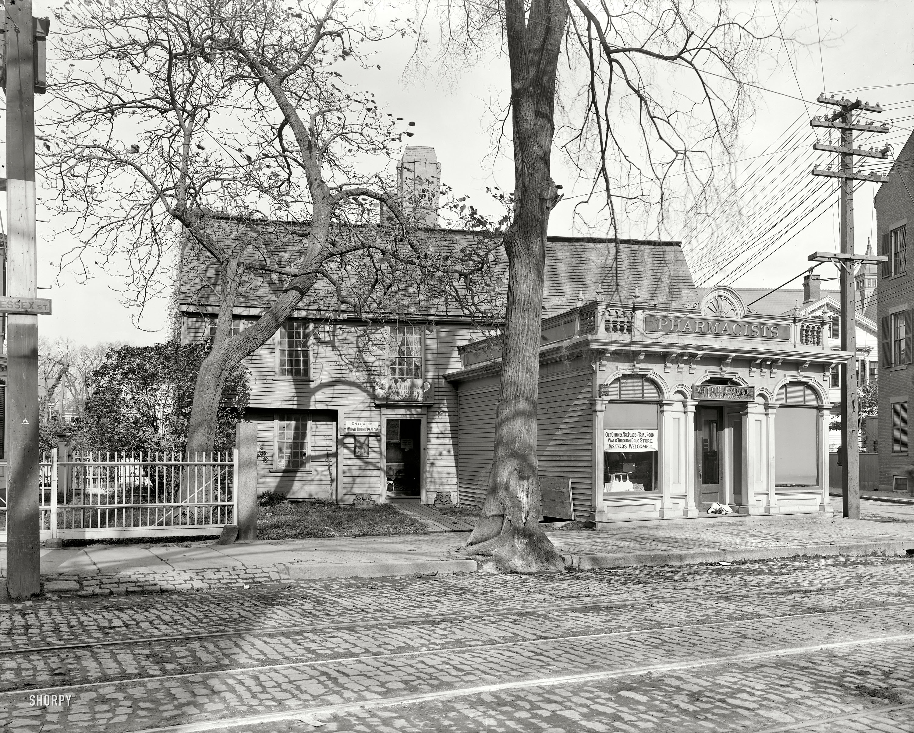 Salem, Massachusetts, circa 1906. "The Old Witch House." In the best Early American tradition, a blending of history and retailing: The Witch House Parlors (enter through the antique store) and Witch House Trial Room (right this way through the pharmacy). 8x10 glass negative, Detroit Publishing. View full size.