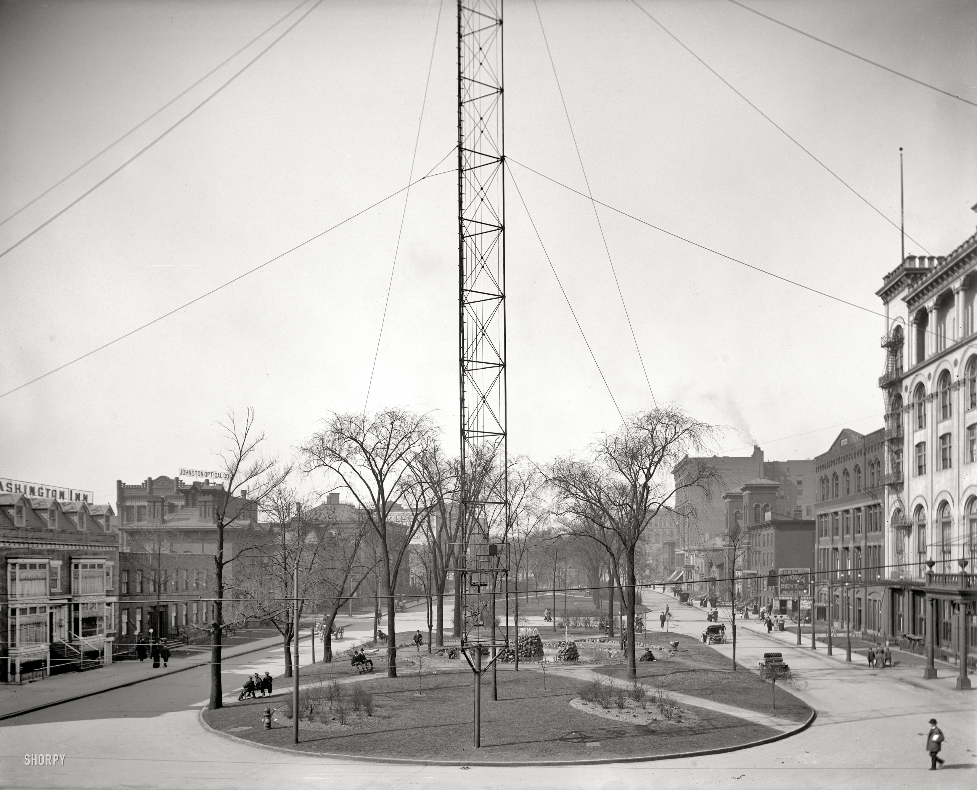 Detroit circa 1907. "Washington Boulevard Park." Adjacent to the Hotel Cadillac, at right, and the site of the ice fountain seen here in several wintertime views. Rising at center is  the base of an arc-lamp standard, part of the city's "moonlight tower" municipal lighting system. 8x10 inch glass negative. View full size.