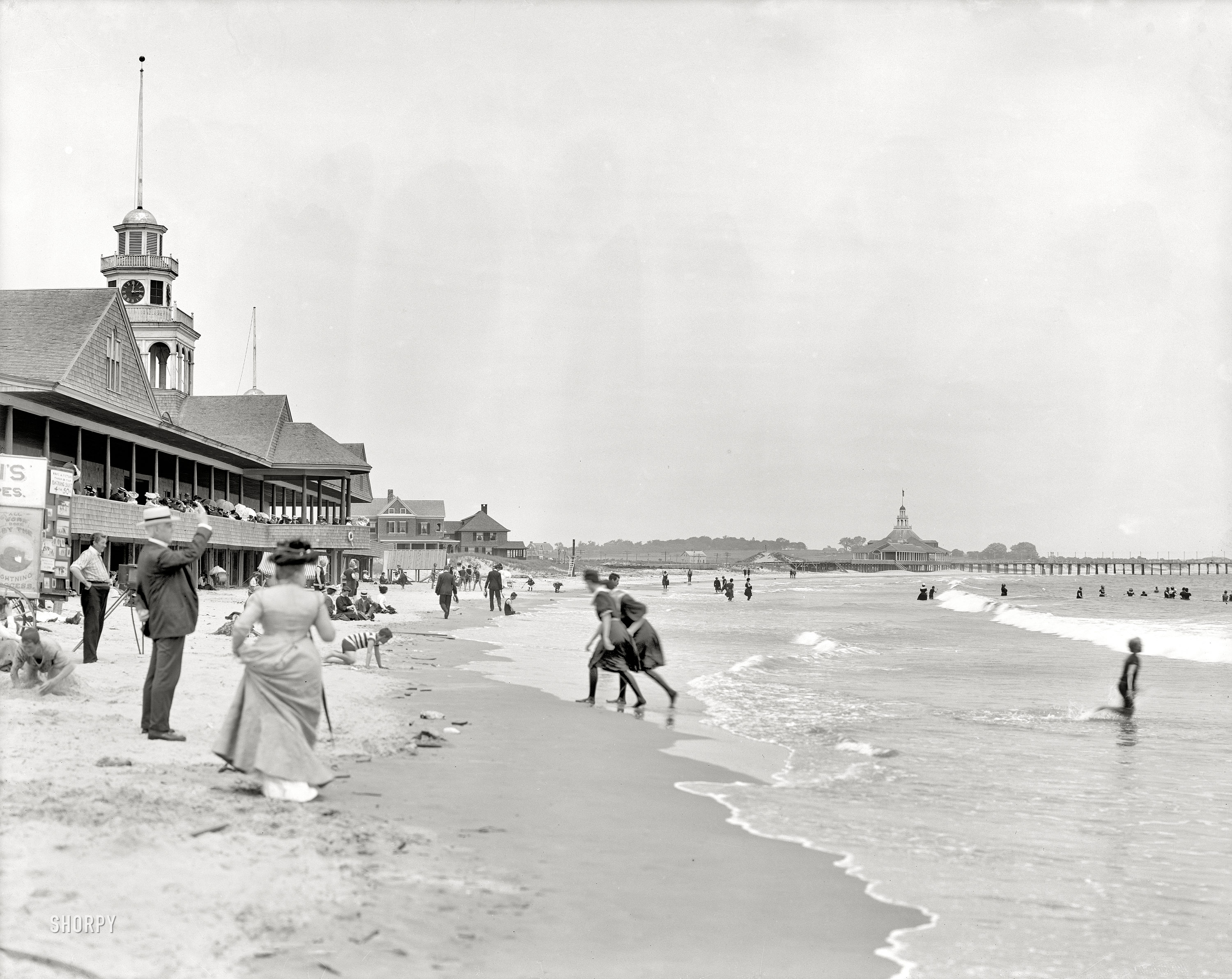Rhode Island circa 1910. "Narragansett Pier bathing beach." Note the photographer and signage to the left: "Want a Picture Taken in Your BATHING SUIT? 4 for 50 cents -- All Work Done by the LIGHTNING PROCESS." 8x10 inch dry plate glass negative, Detroit Publishing Company. View full size.