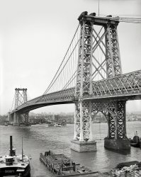 New York circa 1904. "Williamsburg Bridge from Brooklyn." The new span over the East River. 8x10 glass negative, Detroit Publishing Company. View full size.
Another NailThe owners of the ferries on both sides seeing the bridge as another nail in the coffin of their business.
GenerationsLet's see, 1904 ... that was about when the great-grandparents of the hipsters now flocking across the bridge into Williamsburg were born.  As for the bridge, it's one of the relatively few long bridges in the country that carries trains (the J, M and Z subway lines) in addition to vehicles.  
Originally it had four traffic lanes, two on each side of the bridge, with six train tracks in the middle.  Sometime before World War II, four of the tracks were converted to traffic lanes, so today there are four traffic lanes in each direction with the two train tracks in the middle.  The two "inner" lanes in each direction, which occupy the former train tracks, are narrow and hemmed in on each side by the bridge's ironwork.  Driving on them is a scary experience, especially when trains blast by just inches away.
It is true, as another comment noted, that the nearby East River ferries weren't long for this world once the bridge opened.  But they weren't gone forever.  In recent years a very popular ferry service has opened, with a couple of stops not far from the bridge.  It can be a faster route to Midtown and Downtown than the subway.
Beaux art bridgesThe Williamsburgh and the Queensborough are my two favorite bridges in New York I have climbed over up and under every bridge in NY at this point for my business. I remember going on a site walk around 1998 where one of the other engineers almost fell through a rotted floor beam. Since then the bridge has basically been rebuilt 80 percent. It is amazing how it was left to deteriorate. It was so bad that they were actually considering tearing it down and building a new one. The towers were actually leaning in due to corrosion, the solution was to reinforce the land facing section of the towers on both sides. When the trains go over this bridge you have to be extremely careful not to be in any pinch points in the girders you could lose an arm or leg due to the flexing. P.S. it always reminded me of an Erector set drawing.
UglyHands down, New York's ugliest bridge. But combined with its neighbors, the Manhattan Bridge and the Brooklyn Bridge, they make an elegant chorus line up the East River.
And todayView Larger Map
(The Gallery, Boats & Bridges, DPC, NYC)