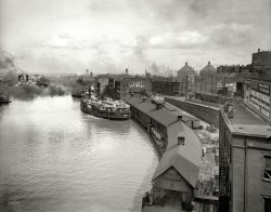 Cleveland, Ohio, ca. 1910. "Cuyahoga River from the viaduct." Sidewheeler State of New York at the Detroit &amp; Cleveland Navigation Co. docks. View full size.
Schlitz the Beer that Made Milwaukee Famous The Schlitz globe stirs the cockles of my heart. The brewery owned a number of retail outlets (taverns) in the Milwaukee area prior to prohibition, each adorned with a ribboned Schlitz globe atop the establishment. After prohibition the company divested itself of the bars. To the best of my knowledge the only remaining building with a globe houses a wonderful Serbian restaurant in the Bay View area of Milwaukee, Wisconsin. (The burek is outstanding.) The old Schlitz Brewery buildings now host trendy bars, retail and office space, lofts, etc.   
State of those White DressesMust have been quite a bit of laundering going on upon return home to wash out all that coal-burning steam engine soot, etc.
Urban Planning Back in the DayNice how they leveled off the top of that slag heap to construct attractive river-view villas.
From a 1900 mapI believe the photographer is on the viaduct crossing the river from the numeral "3". The domed buildings right of center are Union Depot. Today's Browns' Stadium is there now, or just behind them.
The River TodayThe two buildings on the right behind the boat are still there. The two large tanks in the distance are where the office building that's being built (with the crane on top) today is. I used to work just east of the site of the two tanks, on the top of the hill and we used to gaze out the window towards the river all the time. It was all overgrown in the 80s and then cleared and used as an impound lot. Someone then bought the property, cleaned it up and created a legitimate parking lot out of it. In the process they uncovered and removed the stones of the foundations of the two storage tanks. I think they were Standard Oil tanks.
Cleveland Browns stadium would be off to the right of the photo in the far distance, with the land not created yet, as it's built on landfill.
Burp! Though be-fogged with coal smoke, Schlitz is still the beer that made Milwaukee famous. Apparently with a little help from Moxie, A drink that always tasted of ground up walnut hulls to me. 
(The Gallery, Boats & Bridges, DPC, Railroads)