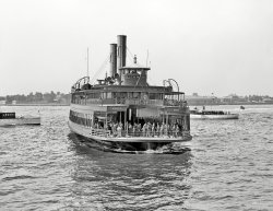 New York circa 1908. "Municipal ferry Richmond." Where men are port and women are starboard, in theory at least. 8x10 glass negative. View full size.
First of the fleetThe Richmond entered service in 1905, one of a new fleet of five boats the city ordered after it had taken control of the ferry from the railroad that had previously operated the service. Each of the boats was named after a city borough, with "Richmond" being the county name for Staten Island.  With a length of 245 feet and a width of 48 feet, it was somewhat smaller than the six primary boats in the current fleet, though larger than the two boats used for overnight service.  By extrapolating from the capacities of the current boats, the Richmond probably carried between 2,000 and 2,300 passengers. 
Several more boats joined the fleet as passenger traffic increased during the 1920's and 1930's.  After almost 40 years of service the Richmond was withdrawn from service in 1944.  It was converted into a barge, presumably to help with the war effort, and went to the scrappers in 1947. 
Smoking habits might be the reason for the separate Men's and Women's entrances. At the time it wouldn't have been socially appropriate for men and women to smoke in front of the other gender, so public spaces such as train stations often had separate waiting/smoking rooms for men and women.  That could have been the case on the ferry too.  In fact, on the upper deck, which doesn't appear to be gender-separated, there are a couple of signs which appear to read "No Smoking."
Unchanged in 1960sThe Hoboken ferries looked exactly the same in the 1960s, except Men and Women had become Smoking and No Smoking. The gates and hardware were the same. I imagine they had gone to diesel though.
Sex Minus SmokingNotice there is NOT a "no smoking" sign on the mens side of the boat. In the more civilized days of travel women were often allowed refuge from the crude habits and language of many of the opposite sex.
(The Gallery, Boats & Bridges, DPC, NYC)