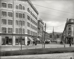 Circa 1905. "Rutland, Vermont -- Center Street." Our title comes from the eatery on the right. 8x10 glass negative, Detroit Publishing Co. View full size.
Pretty much the same todayView Larger Map
Yes,yes I do!
MooIt's hard to tell for sure, given the angles in the 1905 picture and all, but my reasoned guess is that the long-departed U Want A Lunch is now the Bossy Cow ice cream shop. Despite that change, there has been remarkably little change in the streetscape in the 105 years since this photo was taken.
http://goo.gl/maps/fE9Zu
&quot;U Want A Lunch&quot;Possibly a subsidiary of "Uneeda Biscuit".
FinallyA safe place to keep all my marbles!
From the ashesThe buildings in this scene at the corner of Center Street and Merchants Row rose in the aftermath of major fires. The bank building on the right side of the photo replaced a four-story brick block housing the Rutland Savings Bank that burned January 16, 1891. On February 18, 1906, a fire consumed the Bates House and all the other buildings on the left (northeast) corner of Merchants Row and Center Street. A thirty-minute video from the Rutland Historical Society tells the story of that fire. (Those buildings had replaced structures that burned in a 1868 conflagration.) Thus, this photo would have been taken some time after 1906. The "Mead" name on the newly-built, solid office building matches that of one of the City's most prominent citizens, its first mayor and future Vermont Governor John Mead.   
But why was it taken?I wonder why this image was taken.
There are a couple of groups of men standing around on corners for no apparent reason (definitely not posed for the camera) and some individuals peering out windows. Seems like a lot of curiosity about a photographer. Then there is the uniformed man striding purposefully across the street.
[A large part of Detroit Publishing's business was producing picture postcards, frequently of cityscapes, a huge market at the time. -tterrace]
(The Gallery, DPC, Stores & Markets)
