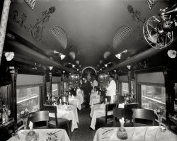 Circa 1902. "Delaware, Lackawanna &amp; Western Railroad dining car." 8x10 inch dry plate glass negative, Detroit Publishing Company. View full size.
More on The SilverwareI believe that the waiter would set the appropriate utensils for each course from the attractive arrangement. There isn’t a lot of room at these tables and I have been to restaurants where the waiter set the silver before each course.
Strange Display?The Silver Ware display on the tables looks awfully strange...wonder why that was placed that way?
DL&amp;WThis is what train buffs call "High Varnish." Mighty nice.
I'm pretty sure I haven't missed an opportunity, every time the DL&amp;W is featured here, to mention that when my grandmother rode that line, over 100 years ago, they all said that the letters DL&amp;W stood for Delay, Linger and Wait.
Style of Long Ago....Incredible elegance that was probably taken for granted back then. Superbly designed (notice the condiment racks on the bulkheads), hat racks, nighttime dining with electric lights overhead. And electric fans! What will they think of next. The use of mirrors that visually make the dining car larger than it appears. This dining car appears to have it all! The man in the aisle does have a bit of a ghostly appearance, though.
According to Lucius BeebeThe varnish diners were meant to give the traveler the same dining experience as the First Class hotel they left and the one they were traveling too.
Re: Strange Display?I didn't notice it at first, but you are correct in that the layout is quite unusual.  Of course, I absolutely love it, and will try the layout the next time I have a formal dinner party.  It almost looks as if it is supposed to represent the railroad crossing sign.
Thanks to a co-worker, the silverware layout has been identified as a "Dragonfly Pattern". - gen81465
Try Your SkillHit the fork handle, flip the knife and spoon into the vase. Win a free order of fries.
Railroad nicknamesRegarding Jazznocracy's comment, it reminded me of a small rail line many years ago that served the timber areas of East Texas. Its official name was the Waco, Beaumont, Trinity and Sabine Railway [WBT &amp; S].
However, due to a constantly precarious financial situation throughout its short life, combined with improper track maintenance as a result, most folks said WBT &amp; S stood for Wobbledy, Bobbledy, Turnover and Stop.
It would be interesting to find out how many other "unofficial" railroad nicknames were out there using the letters of the rail companies.
DL&amp;WAlong with "Delay, Linger and Wait," another DL&amp;W nickname was "Dread, Long and Weary." My dad was a lifelong DL&amp;W/EL employee and I often heard those as a kid.
(The Gallery, DPC, Railroads)