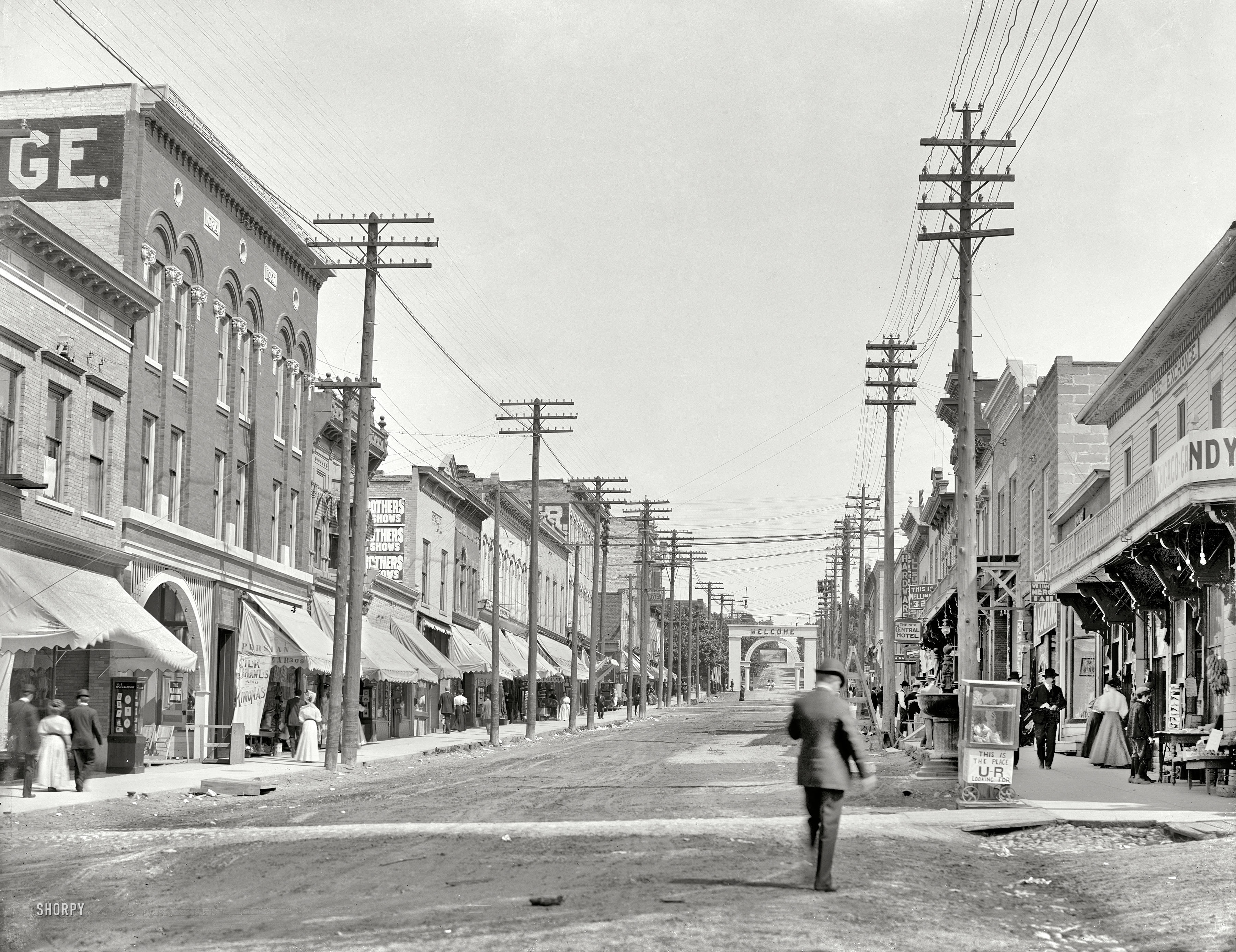 Circa 1908. "Lake Street, Petoskey, Michigan." A bustling hub of commerce offering silk shawls, "kimonas" and "the place U-R looking for." As well as a nice arch. 8x10 inch glass negative, Detroit Publishing Company. View full size.