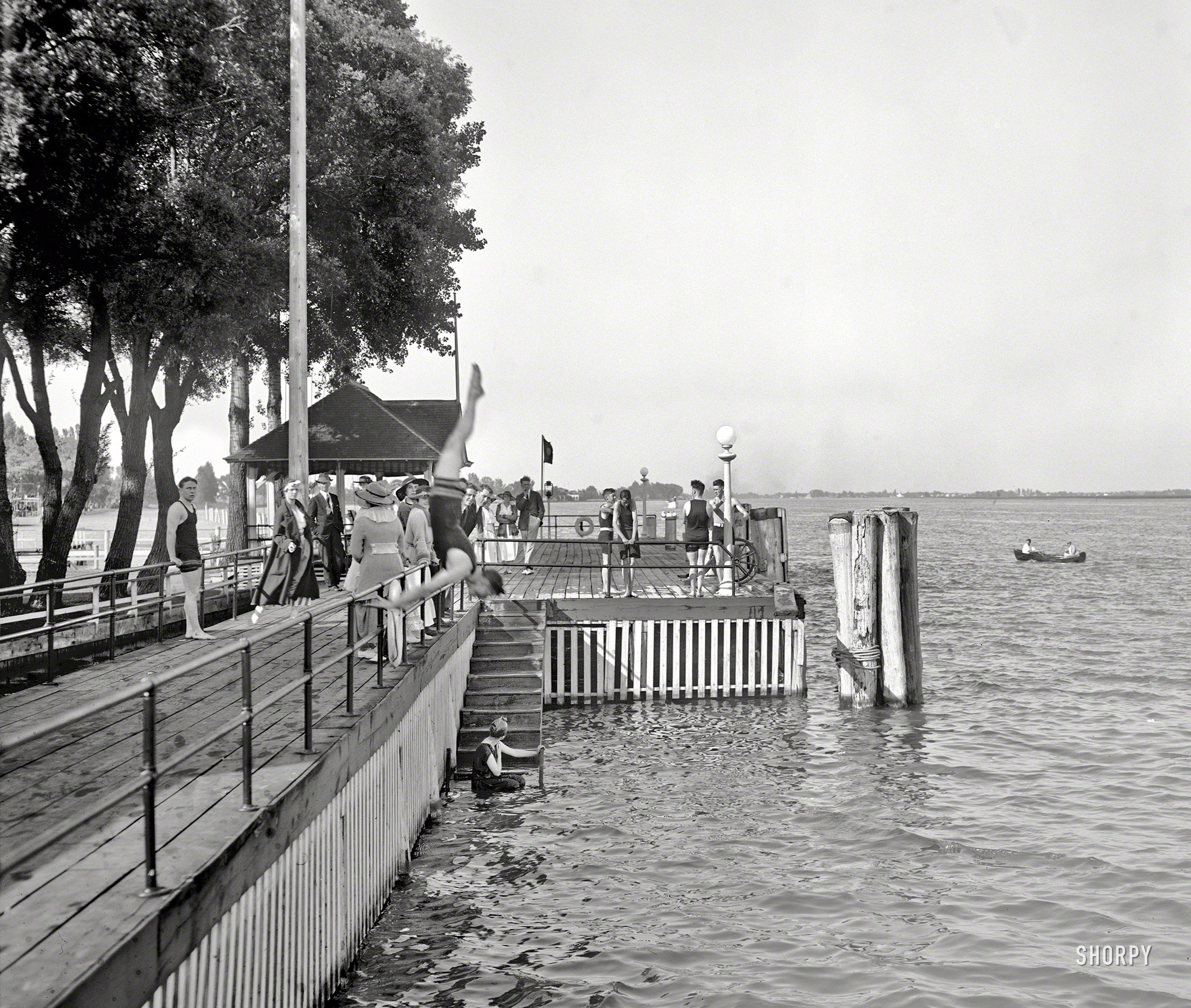 Circa 1910. "Bathing at the Old Club, St. Clair Flats, Michigan." With a rowboat in the water and a showboat in midair. 8x10 glass negative. View full size.
