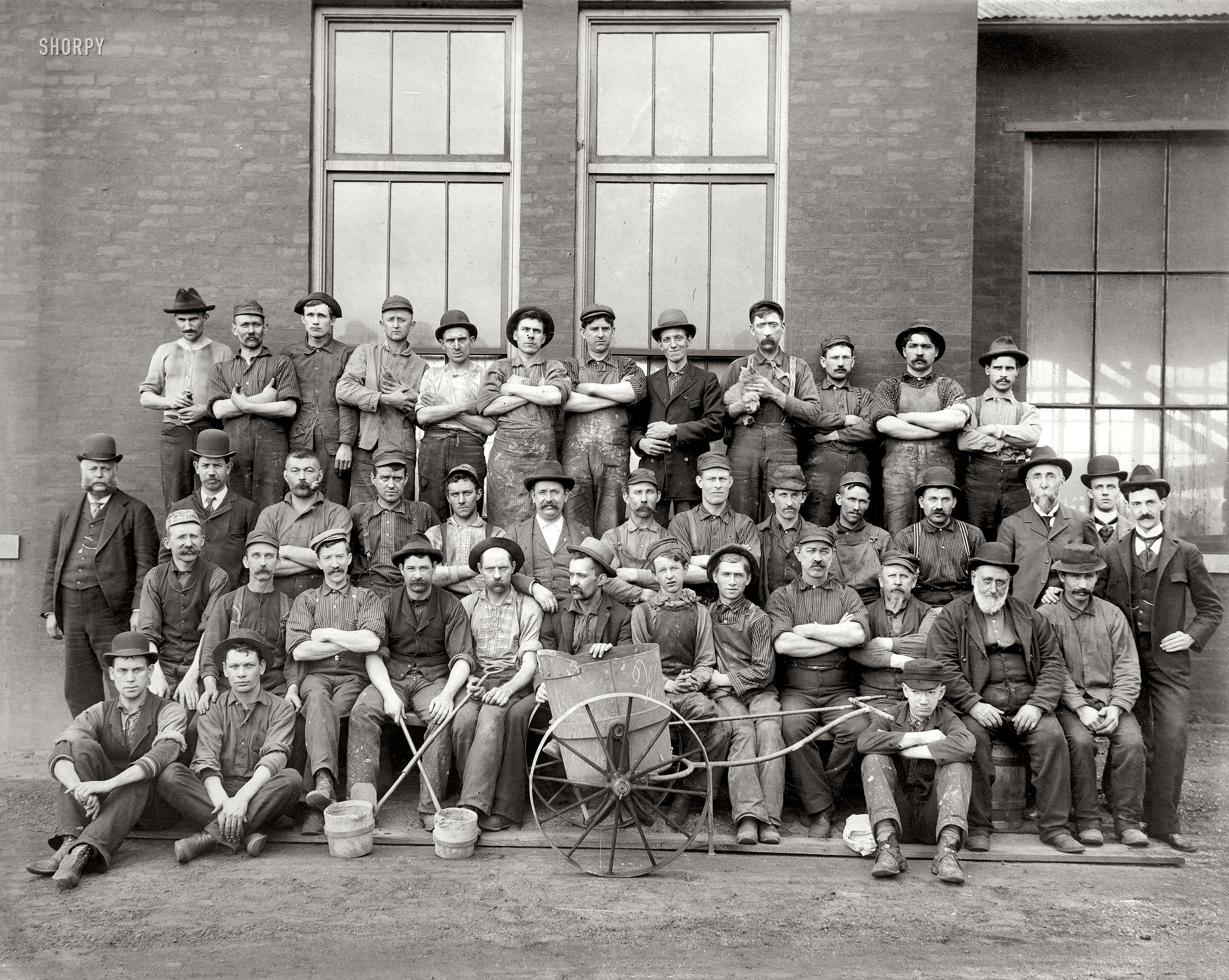 Detroit circa 1903. "Foundry and machine shop, Leland & Faulconer Mfg. Co." With bearded proprietors Robert Faulconer (left) and Henry Leland standing at either end, and two shop mascots in the top row. In 1905 the company, which made car engines, merged with Cadillac Automobile Co. Some years after selling Cadillac to General Motors, Leland started the Lincoln Motor Co., which was eventually bought out by Ford. 8x10 inch glass negative. View full size.