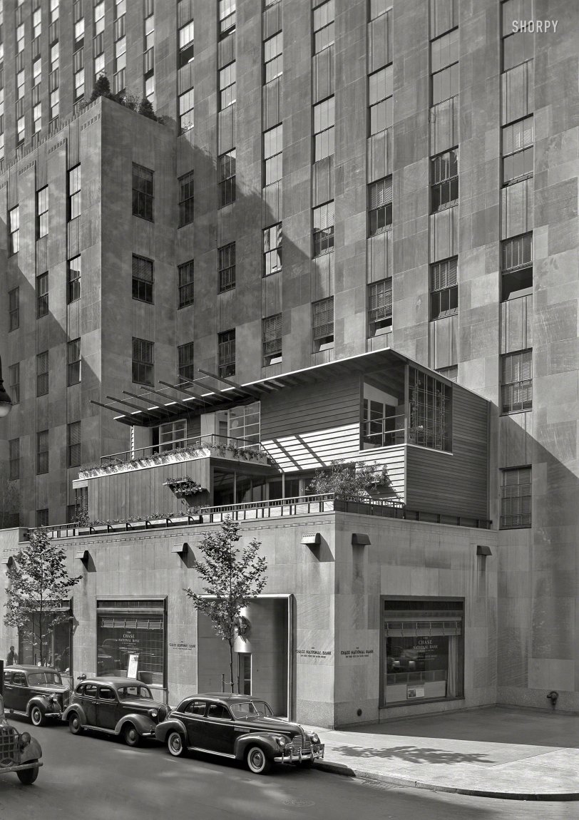HOME EXHIBIT PLANNED
Dwelling Rises on Terrace in Rockefeller Center
&nbsp; &nbsp; &nbsp; &nbsp; NEW YORK -- On the second-floor terrace of the International Building at 51st Street near Fifth Avenue, a seven-room dwelling is under construction as the focal point in what is designed to be a home-building center and exhibit. It is being erected by the Rockefeller Home Center, successor to the Permanent Exhibition of Decorative Arts and Crafts (PEDAC).
&nbsp; &nbsp; &nbsp; &nbsp; The dwelling is of modern design by Edward D. Stone and the exterior is of redwood. In the first floor is a "three-purpose" room with a glass-enclosed side opening onto a terrace. Construction of the exhibition house, which is sponsored by Collier's magazine, is under direction of Irons &amp; Reynolds, contractors.
-- News item, May 16, 1940

July 15, 1940. "Collier's House at PEDAC, New York City. Exterior from below. Dan Cooper, decorator; Edward Durrell Stone, architect." Large-format acetate negative by Gottscho-Schleisner. View full size.
