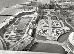 March 30, 1955. "Fontainebleau Hotel, Miami Beach. Roof view of pool, cabanas and garden. Morris Lapidus, architect." The valet will be happy to park your Cadillac. Large-format acetate negative by Samuel H. Gottscho. View full size.
Long time no seeLOVE.LOVE. the diving structure.  Too bad they don't do many of these anymore due to liability.  That would have been a ball!  I am too old now probably but just the right age to remember them!!!
Bellhop!The squids are in the garden again.
Diving platformWow.....now THAT's a platform.
As a kid we would have lived all day on that thing.
Parents would have to drag us off it at the end of the day.
Goldfinger slept here. Welcome to Miami Beach! One of the best sequences from the movie shows the Fontainebleau Hotel.

Attention! -- you in the pool!the pool is for effect only !
Where were you when the fountain blew ?I never could figure it out. They built a fabulous hotel, gave it an elegant French name, then must have asked Jerry Lewis how to pronounce it.
[Exactly right. "FON-tin blow" if you're from France; "fountain-blew" if you're Jerry. - Dave]
I can just seeAuric Goldfinger cheating at Canasta poolside, and I can imagine James Bond thwarting it all...
Goldfinger trickeryUnfortunately for Sean Connery and Gert Frobe, neither of them got Fontainebleau vacations; all their scenes were filmed at Pinewood Studios in England. Those in which they appear to be at the hotel were accomplished by means of matching studio sets, rear-projection or traveling matte effects shots and, in one case, a body double for Frobe. Speaking of Frobe - or rather speaking for Frobe - English actor Michael Collins dubbed all of his dialog, as Frobe's accent proved incomprehensible. Frobe is heard in the German-language version, however, having re-dubbed himself.
That VideoI also shows that the original building, in the posted photo, was destined to expand and was really only about half finished in 1955.  Haven't been there in a while, hope much of the original flambounce has remained.  Lapidus always wanted his hotel designs to help you escape into a fantasy world, as far removed from your everyday life as possible.
[flambounce (flam' bounce), n., a spectacular dive from a swimming pool platform at a resort hotel, esp. in Florida. Origin: Shorpy, 2013. -tterrace]
HA!  Fantasy worlds call for fantasy words.
Planned before pop-ups, possiblyI see at least four hose sprinklers just like the couple I use in my lowly Baltimore yard. Either this joint was created before pop-up watering nozzles were invented or, judging by that puny, laughably underscale fountain, the budget had no room for such flambounciness.  Say, what's with my "watering nozzles" becoming a hotlink to a commercial site? Same thing happens with my own photography site.
[Your computer has picked up some malware; those links appear only to you. -tterrace]
(tterrace, thank you for the note.)
(The Gallery, Gottscho-Schleisner, Miami)