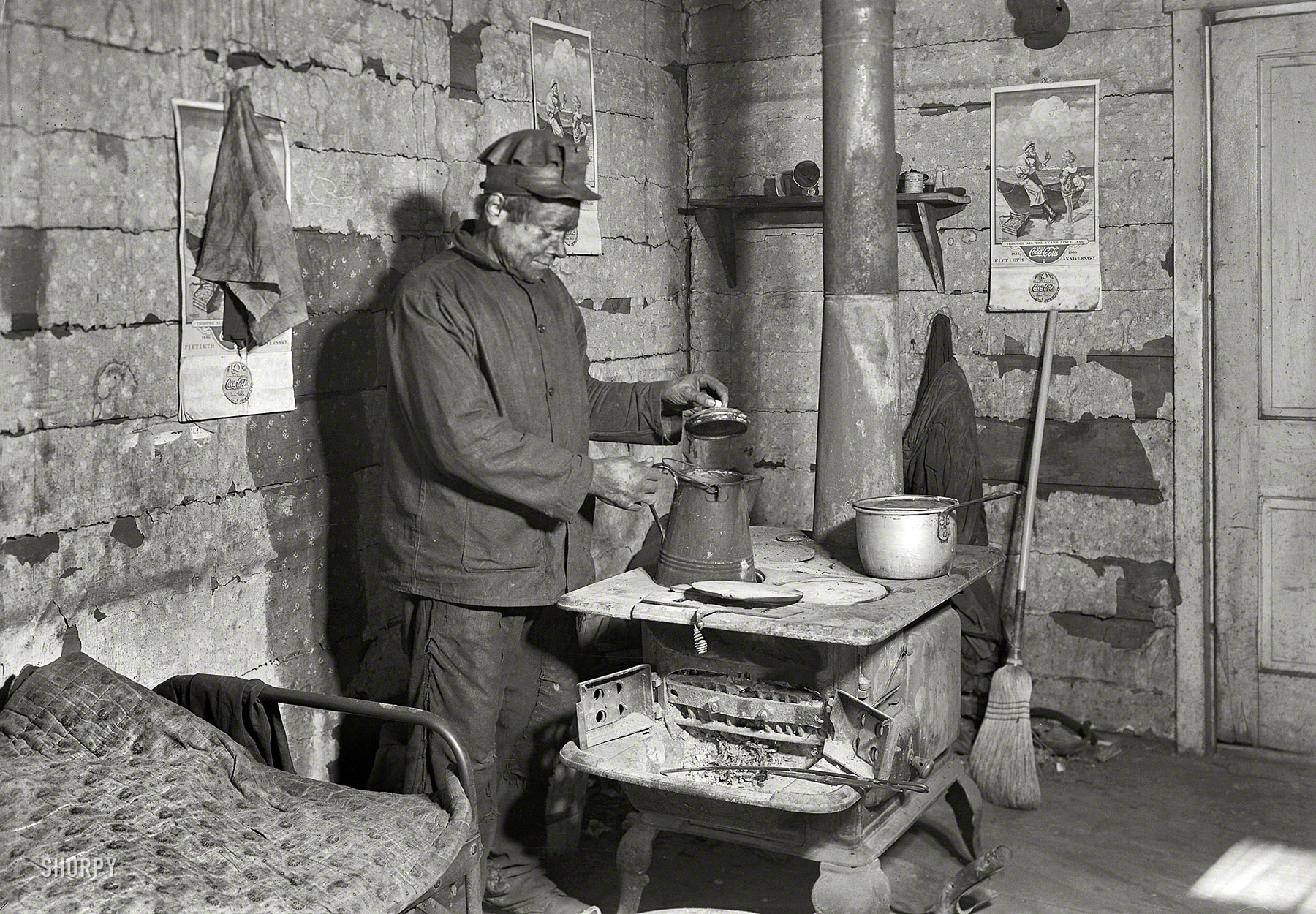March 1937. Scotts Run, West Virginia. "Employed bachelor coal miner at home in Sessa Hill. This scene is typical of hundreds of bachelors who belong to a group of immigrants whose family was separated by immigration restrictions. This man may, or may not, have a wife in another country." Photograph by Lewis Wickes Hine. Decor by Coca-Cola. Large format acetate negative. View full size.
