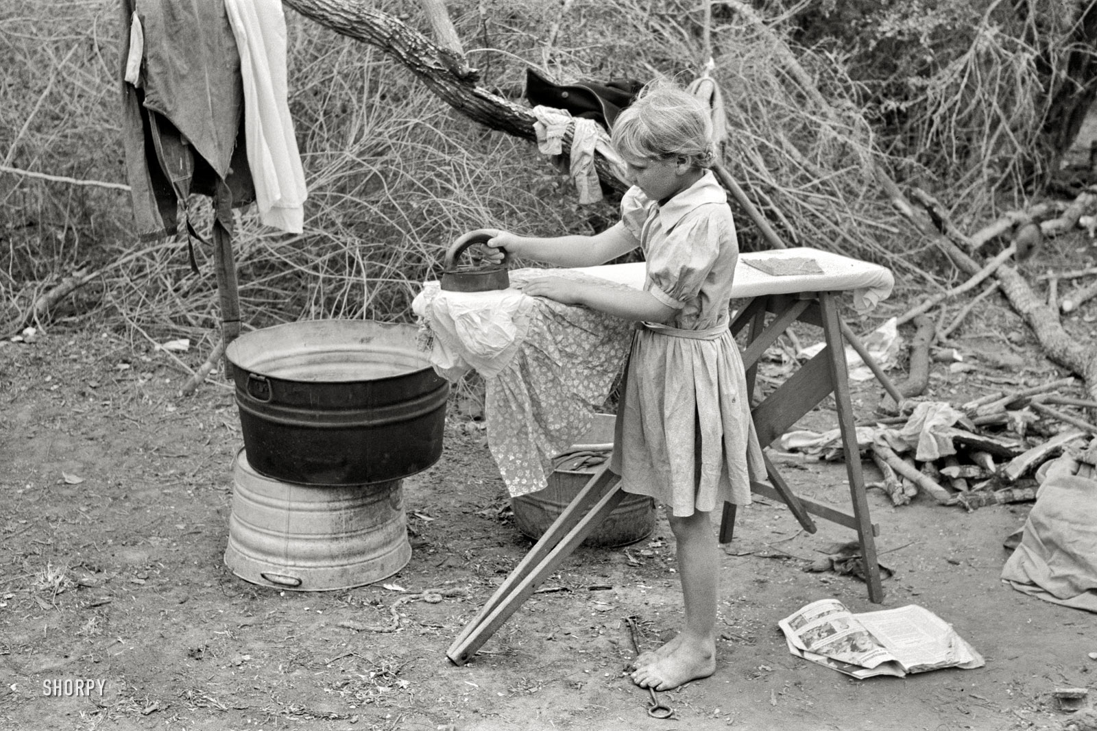February 1939. "Child of white migrant worker ironing in tent camp near Harlingen, Texas." 35mm negative by Russell Lee for the FSA. View full size.