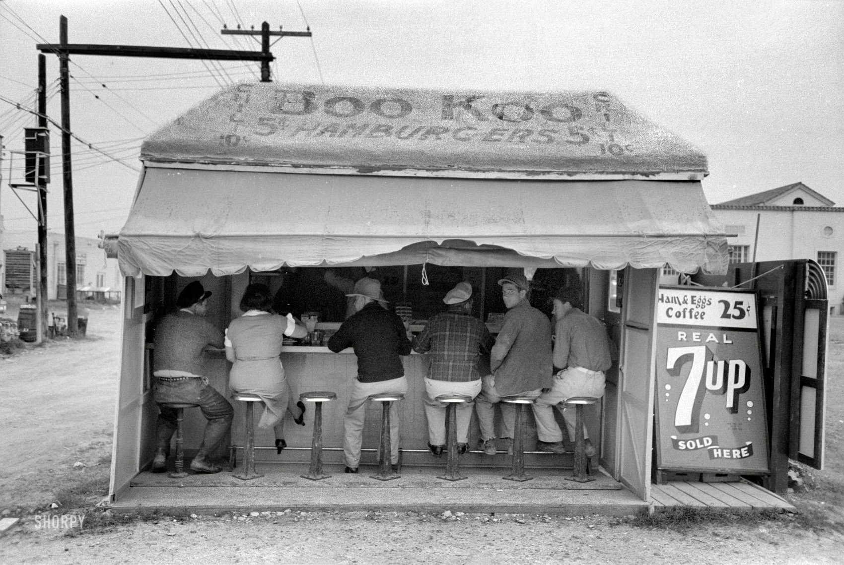 February 1939. "Hamburger stand in Harlingen, Texas." Burgers 5 cents, chili a dime, breakfast two bits, the 7up is real. Photo by Russell Lee. View full size.
