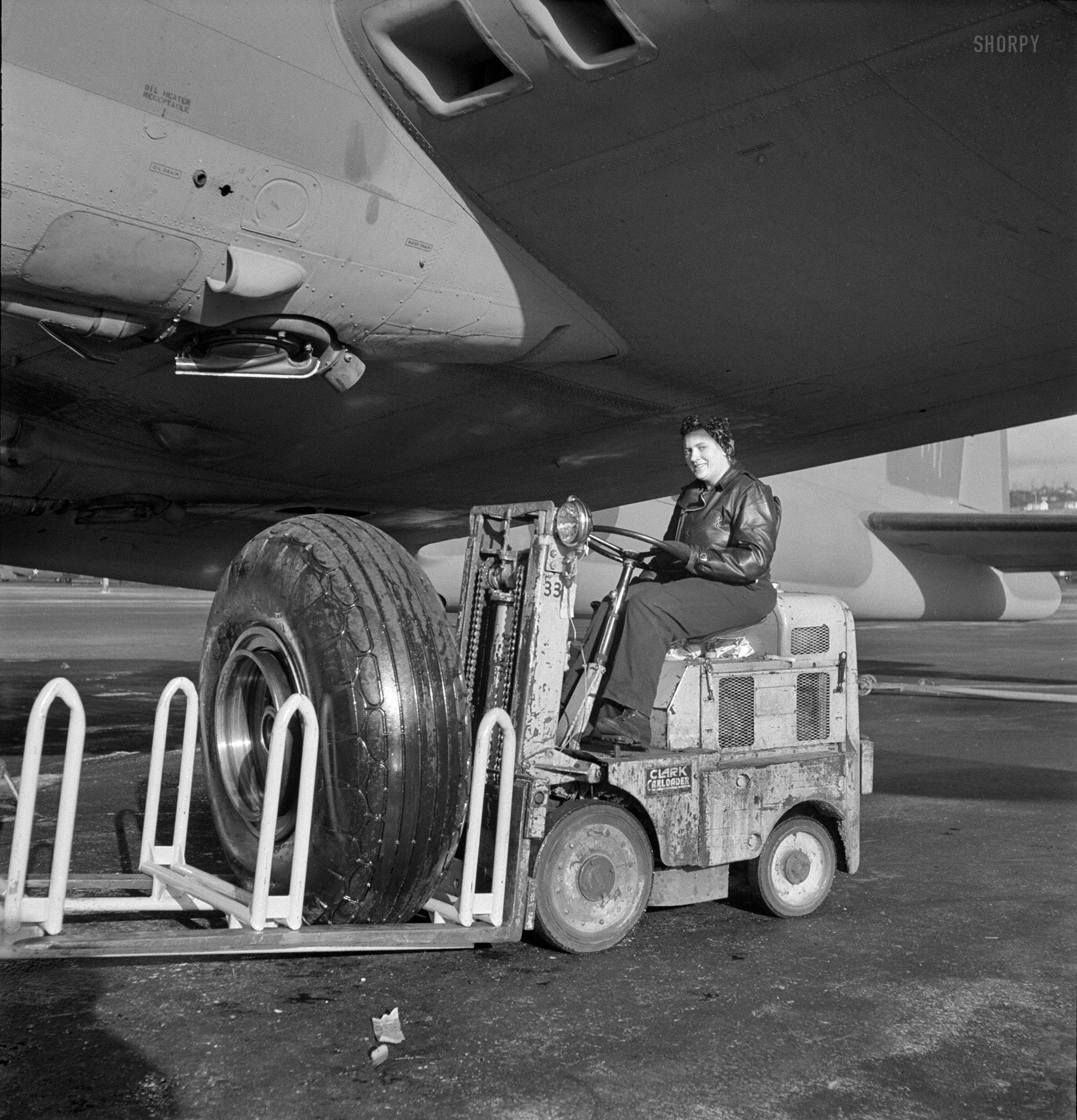 December 1942. "A landing wheel, with its huge rubber 'shoe,' is trundled out in a service tractor to a new B-17F (Flying Fortress) bomber awaiting completion at Boeing's Seattle plant. The tractor operator, like half of the plant's workers, is a woman." Photo by Andreas Feininger,  Office of War Information. View full size.
