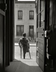 June 1942. Washington, D.C. "Young boy standing in the doorway of his home on Seaton Road in the Northwest section. His leg was cut off by a streetcar while he was playing in the street." Photo by Gordon Parks. View full size.
