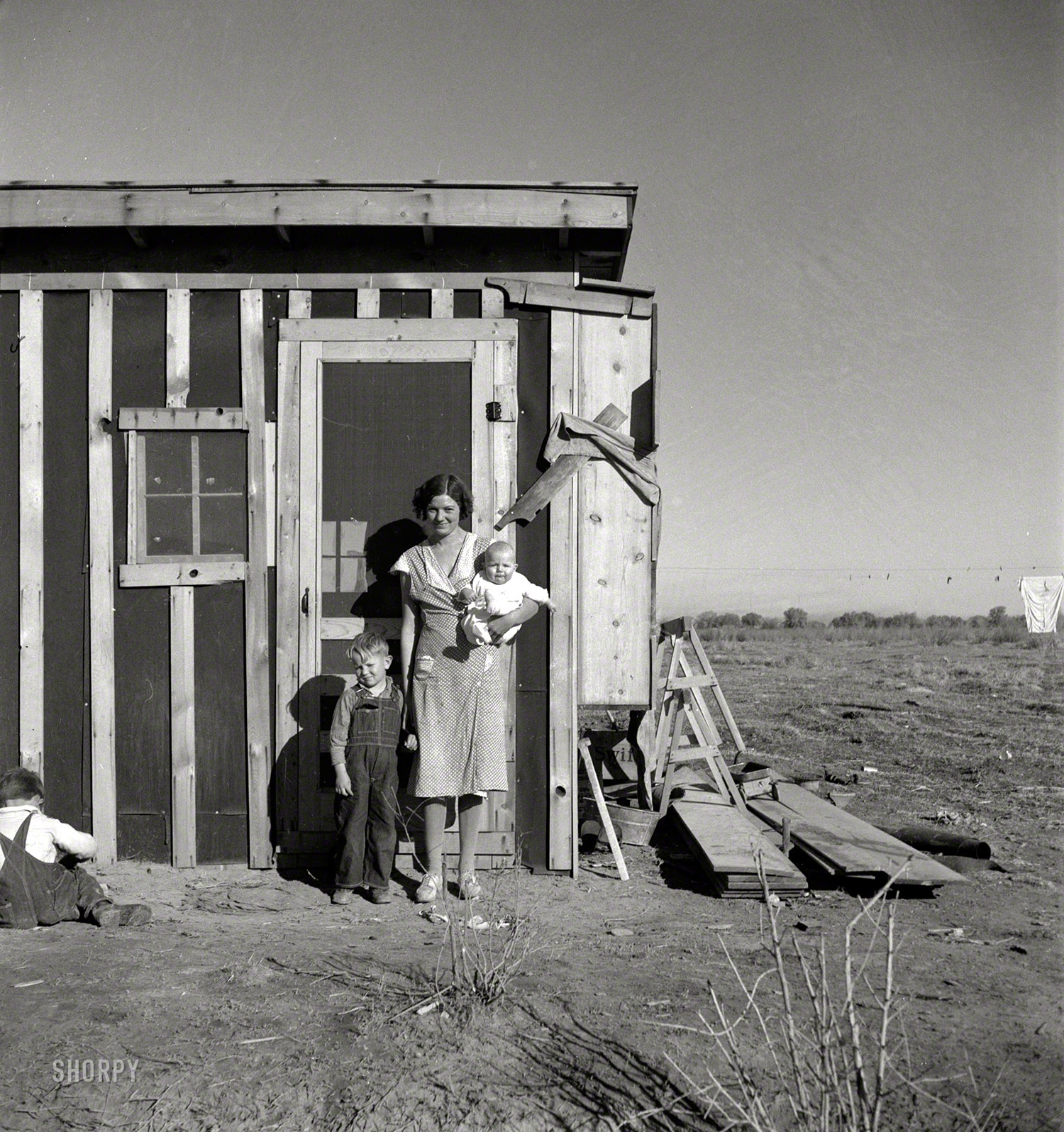 December 1935. "Resettled at Bosque Farms project in New Mexico. Family of four from Taos Junction shows temporary dwelling." Medium-format negative by Dorothea Lange for the Resettlement Administration. View full size.