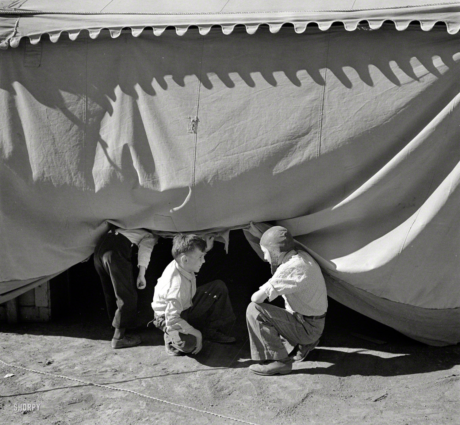 April 1936. "Sneaking under the circus tent. Roswell, New Mexico." Photo by Arthur Rothstein for the Resettlement Administration. View full size.