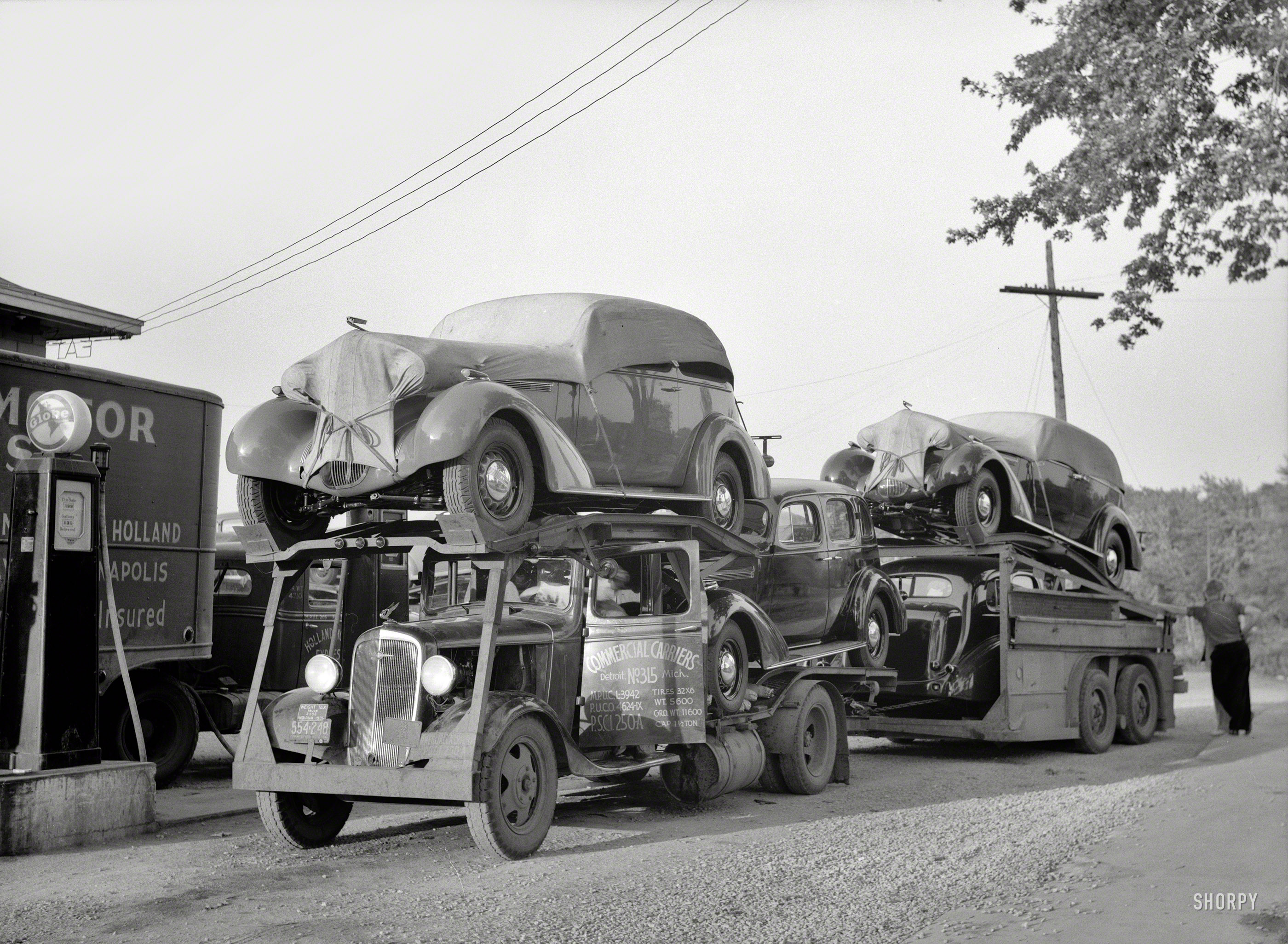 May 1936, somewhere in Indiana. "Auto transport at gas station." Everyone has a nice hood ornament here. Photo by Carl Mydans. View full size.