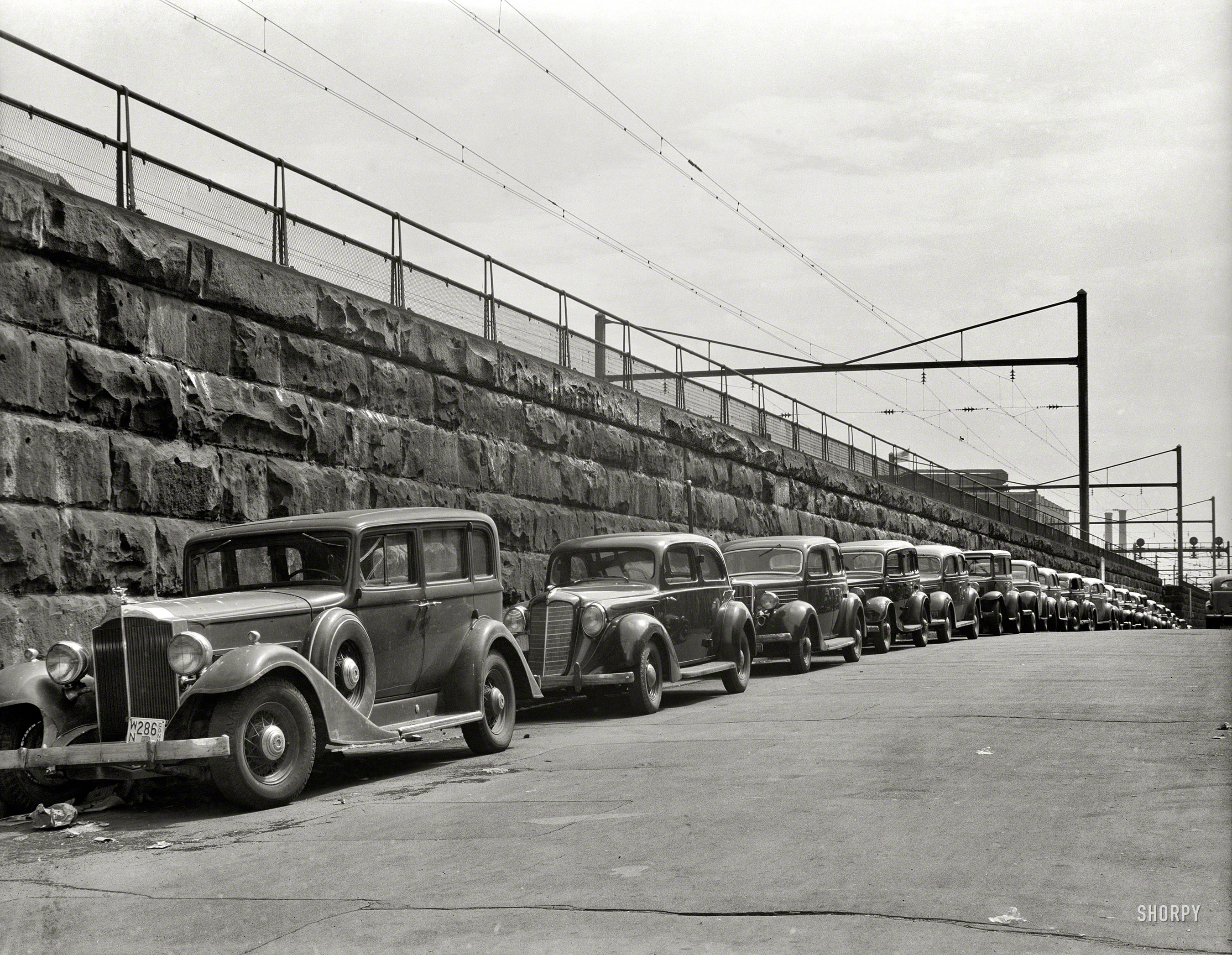 An unlabeled photo of cars parked next to train tracks from the FSA archive taken around 1939. Who can pinpoint the location? View full size.