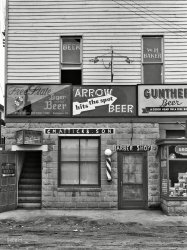 Sept. 1937. "Barber shop and pool hall. Berwyn, Maryland." Between rounds, you can get a haircut. Medium-format negative by John Vachon. View full size.
Clever sloganFree State was located on Baltimore's Hillen Street, I believe; the site is now occupied by a Baltimore fire house. Their slogan was one of the neatest going: "Your Thirst Choice". Unfortunately for them, their beer WASN'T Baltimore's first choice [or second or fourth...].
Shaefer took over Gunther's and dropped the name, dropped the recipe and thought Baltimoreans would flock to Shaefer. It didn't happen.
Globe Brewing had a lineage dating back to the late 18th Century. 
All gone todayArrow Beer was a brand of Baltimore's Globe Brewing and lasted until 1963.  Gunther Beer merged with Schaefer around the same time, with the Baltimore facility lasting about another decade.  Free State closed in 1952; there is now a popular Kansas microbrewery of the same name but I don't believe they are related.
I Wondered What The Good Head Was OnNow we know.
I only need a shave.Make mine a shorty and a shot.
Handled CorrectlyYou could stay there forever. No need to go home.
Trolley Tripper?With one or two transfers John Vachon could have easily traveled from his Rosslyn, VA photo locations to this one. Most of Berwyn's business district was within a block or so of the trolley line. In fact, I have a dim memory of my dad and I visiting a barber shop there in the 50's that sat right next to the track.
Old Hopfheiser (Hop-Hi-Zer)Hopfheiser Beer was contract brewed for a distributor in the Washington, DC area by the Globe Brewing Co.
The beers may be gone, butThe building lives on at 5000, 5002 and 5004 Berwyn Road, Berwyn Heights. Berwyn Road is of of US Route 1 just north of the University of Maryland. 
Short walk to trolleyThe trolley ran on what is now the College Park Trolley Trail that is approximately 50 yards away. The correct current address is 5002 and 5004. 5000 is corner building not pictured in Vachon image.  
Growing up a GuntherGrowing up in Baltimore with the last name of Gunther could be hazardous. I was always subject to any juvenile humor that would turn around a jingle to my disadvantage. 
The ad in the comment below was before my time thankfully but I still remember being playfully taunted by my friends whenever a new campaign would roll out. My bearing the brunt of the jibes was finally paid off when in 1954 the Baltimore Orioles came to the American League and Gunther became their TV sponsors and out in left field was a big scoreboard with my last name along the bottom.
(The Gallery, Eateries & Bars, John Vachon)