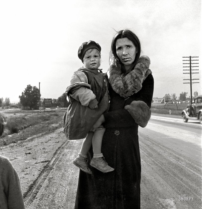 February 1939. "On U.S. 99 near Brawley, Imperial County, California. Homeless mother and youngest child of seven walking the highway from Phoenix, Arizona, where they picked cotton. Bound for San Diego, where the father hopes to get on relief 'because he once lived there.'" Medium-format nitrate negative by Dorothea Lange for the Farm Security Administration. View full size.