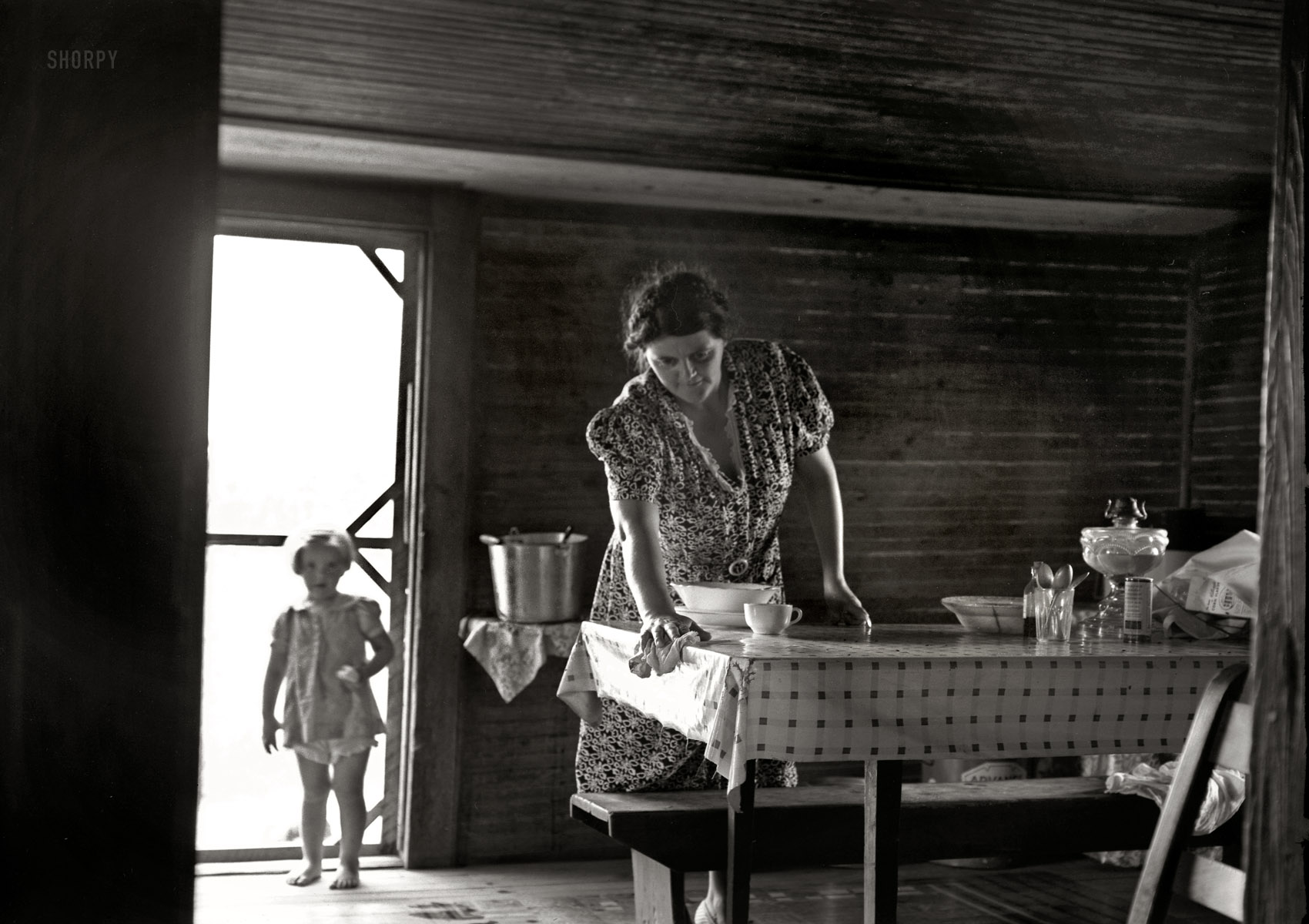 July 1939, Person County, North Carolina. Wife and child of tobacco sharecropper. The littlest girl comes in from outside for something to eat while Mother is doing her housework. The child next to the baby is called in this country the "knee baby."  View full size. Photograph by Dorothea Lange.