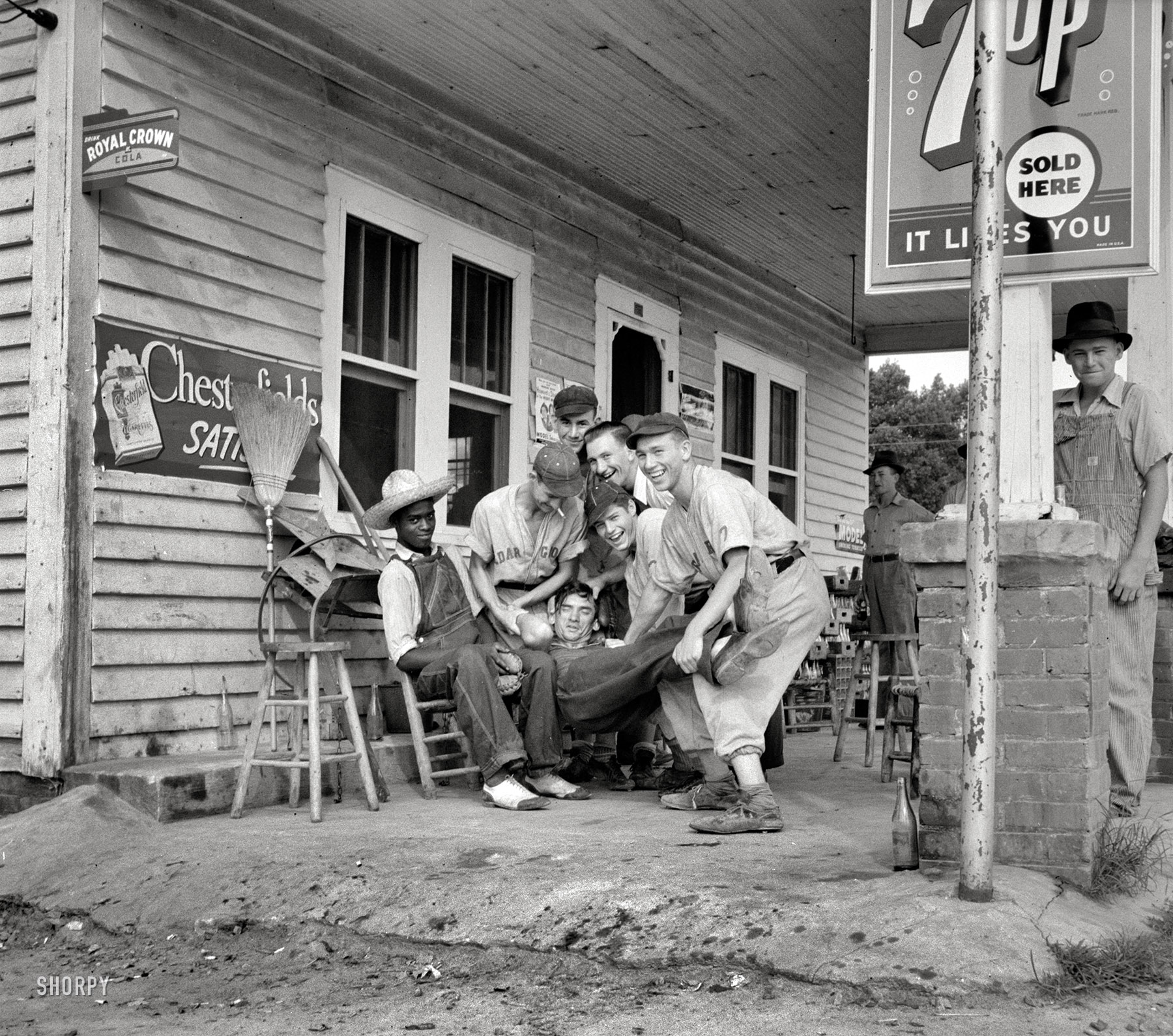 1939. "Fourth of July near Chapel Hill, North Carolina. Rural filling stations become community centers and general loafing grounds. The men in the baseball suits are on a local team which will play a game nearby. They are called the Cedargrove Team." Medium-format negative by Dorothea Lange. View full size.