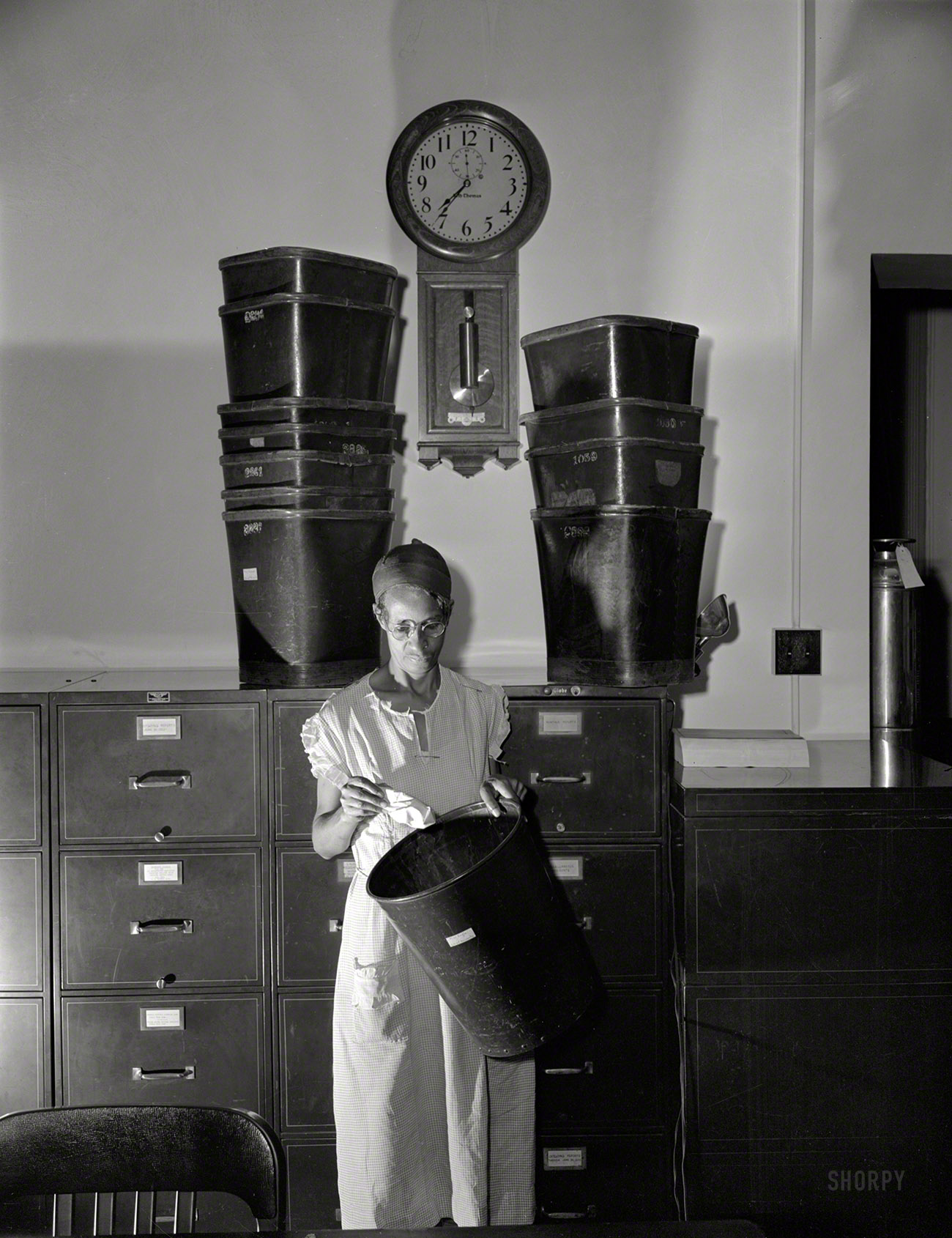 August 1942. "Ella Watson, government charwoman who provides for a family of six on her salary of $1,080 per year. She has been a federal employee for 26 years." Label on the wastebasket: "Miss Engle, Div of Recounts." Large format negative by Gordon Parks, Office of War Information. View full size.