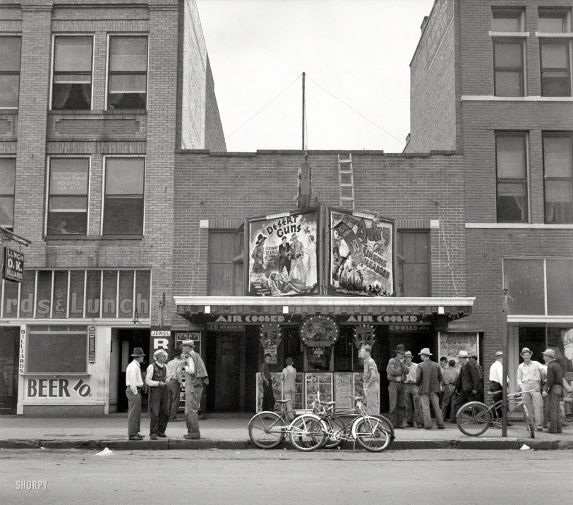 June 1937. "Oklahoma City. Idle men attend the morning movies. There are three such movies in one block." Now playing: Desert Guns and The Singing Vagabond. Photo by Dorothea Lange, Farm Security Administration. View full size.
