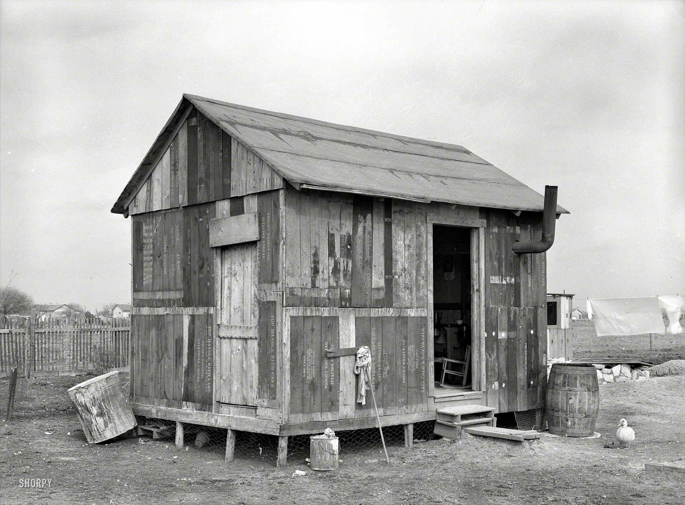 March 1939. "House in Mexican section made of discarded airplane engine crates. San Antonio, Texas." Note feathered mascot. Medium-format nitrate negative by Russell Lee for the Resettlement Administration. View full size.