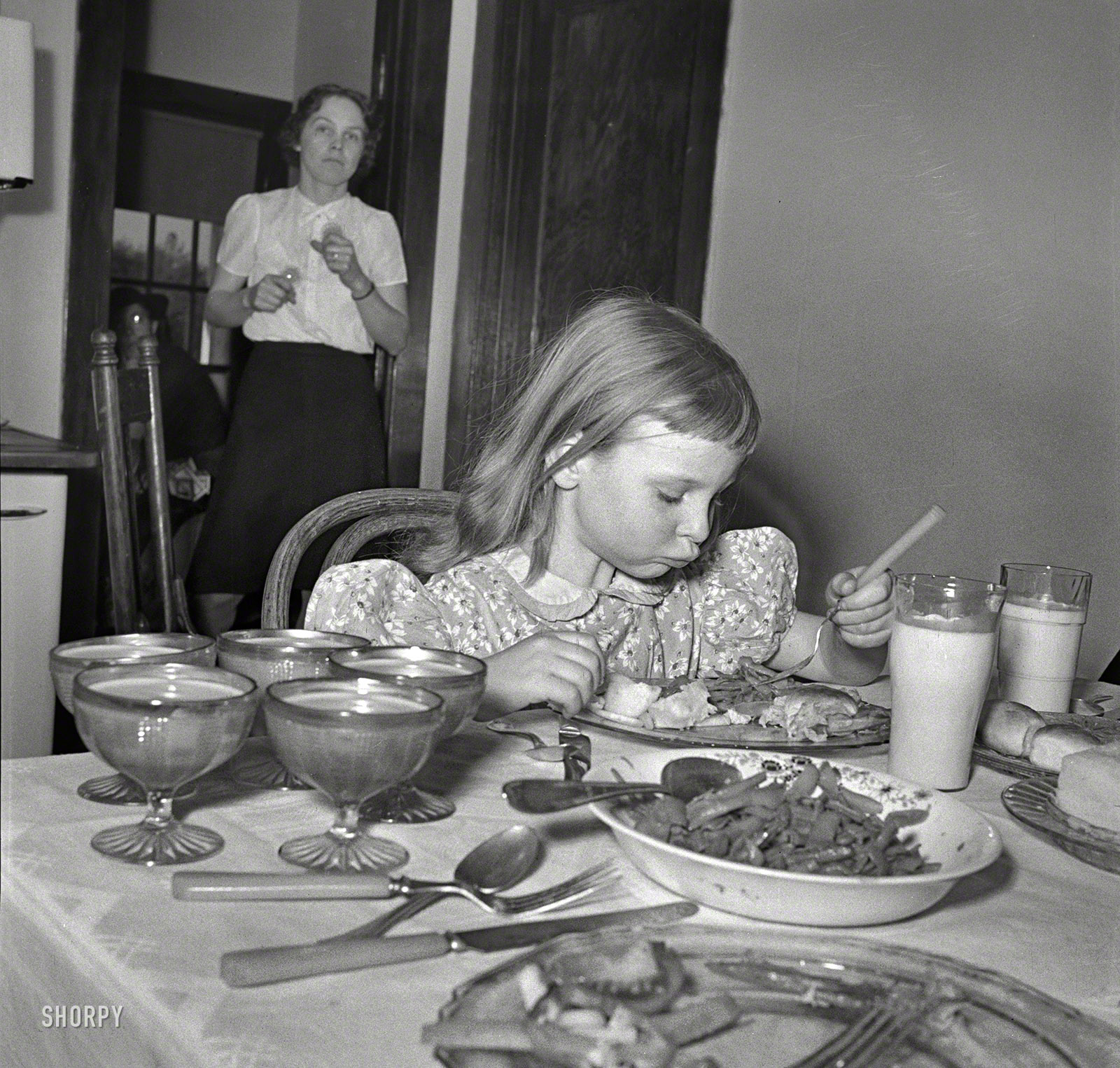 Spring 1942. "Little girl on a farm in Maryland, learning to eat vitamins. 'Balanced meal' on the table of a Farm Security Administration client in Calvert County." Photo by John Collier for the Office of War Information. View full size.
