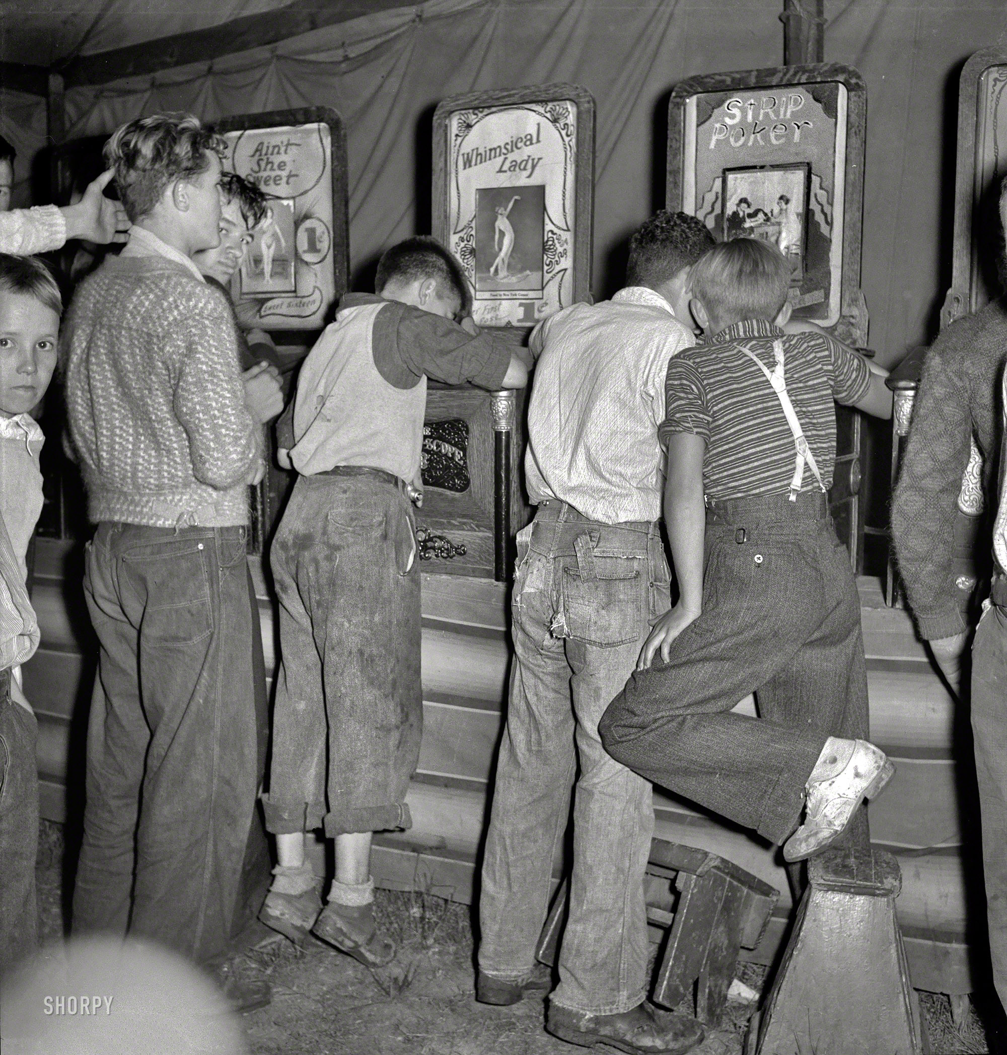 September 1938. " 'It's a dirty gyp,' say the mine workers' sons in the penny arcade at outdoor carnival. Granville, West Virginia." Stepstools helpfully provided for the shorter cineastes. Photo by Marion Post Wolcott. View full size.