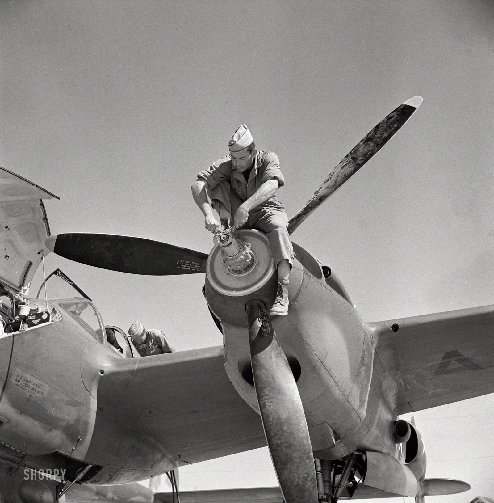 May 1942. "Working on the nose of an engine on an interceptor plane. Lake Muroc, California." Photo by Russell Lee for the OWI. View full size.